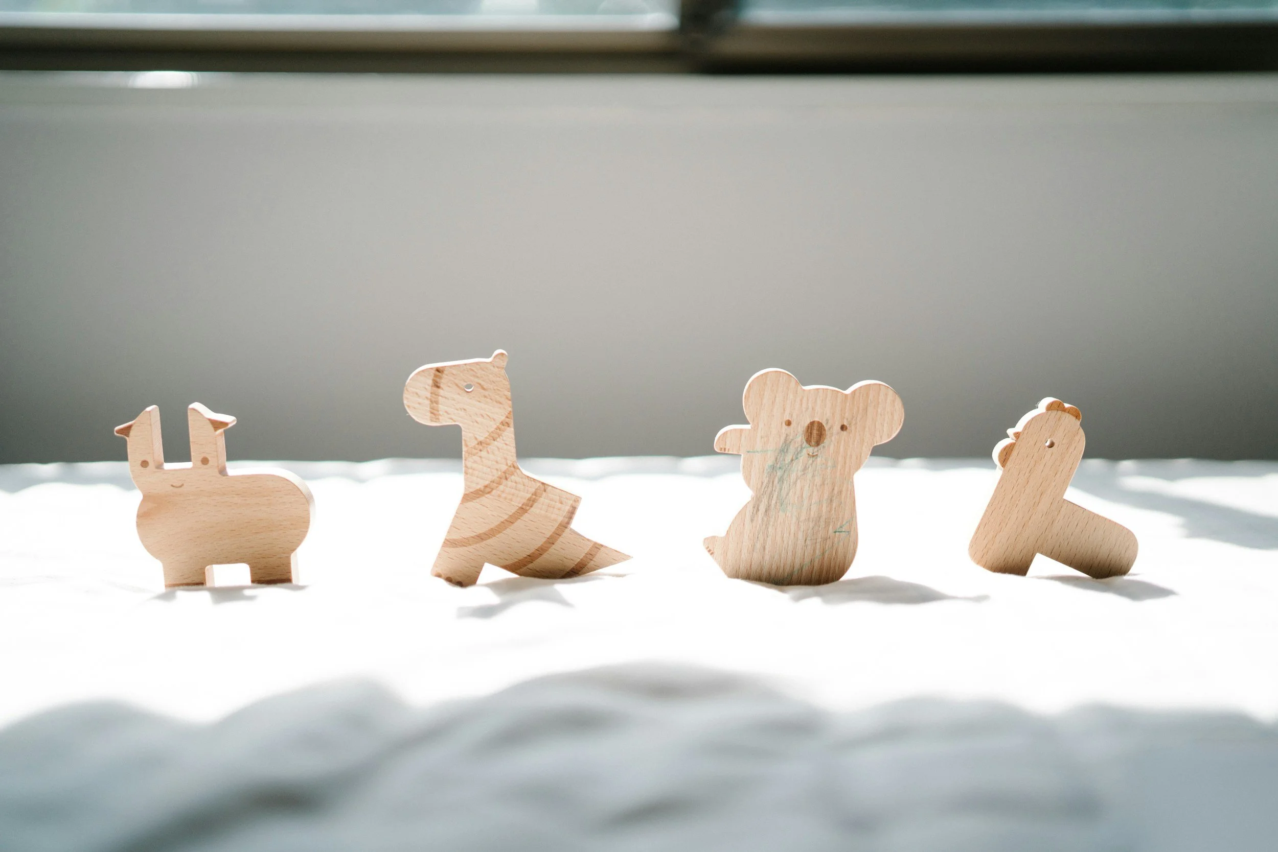 Figura di cinque animaletti di legno decorativi e stilizzati disposti in fila.