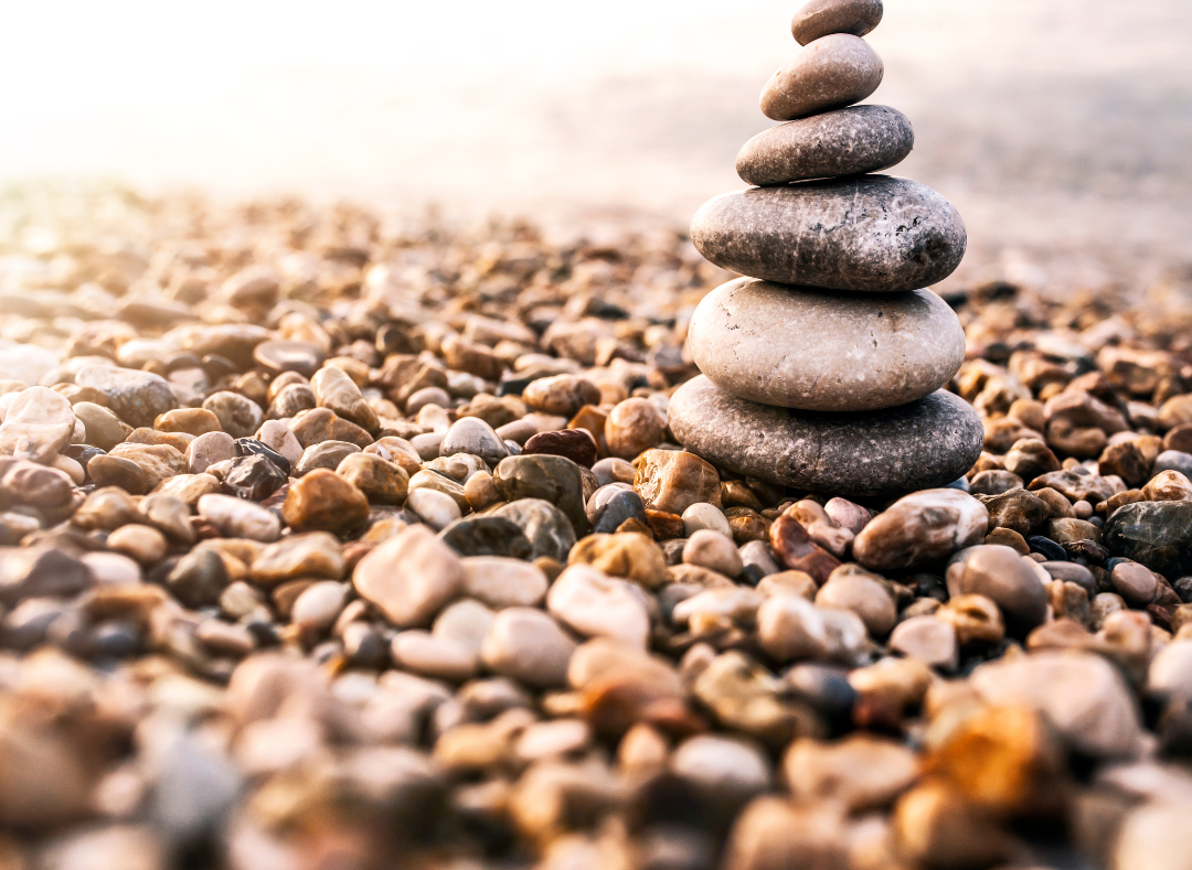 Balanced stones on a pebble beach at sunset.