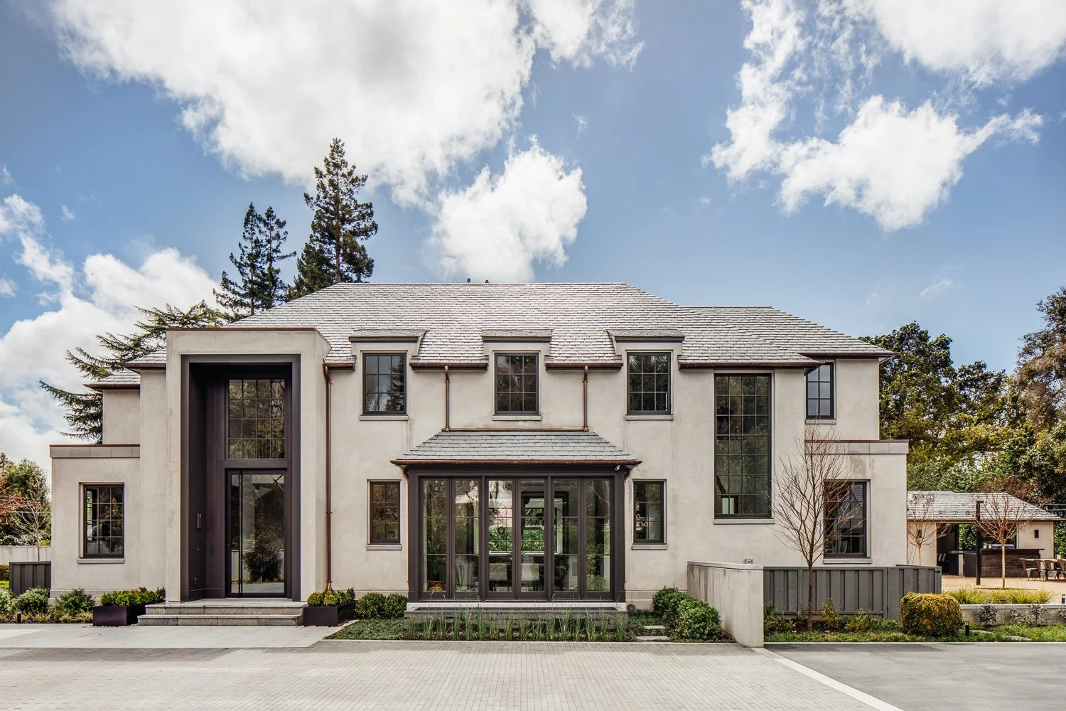 An exterior entrance view showing a paved driveway, front door area, and a smooth rendered facade of the residence.