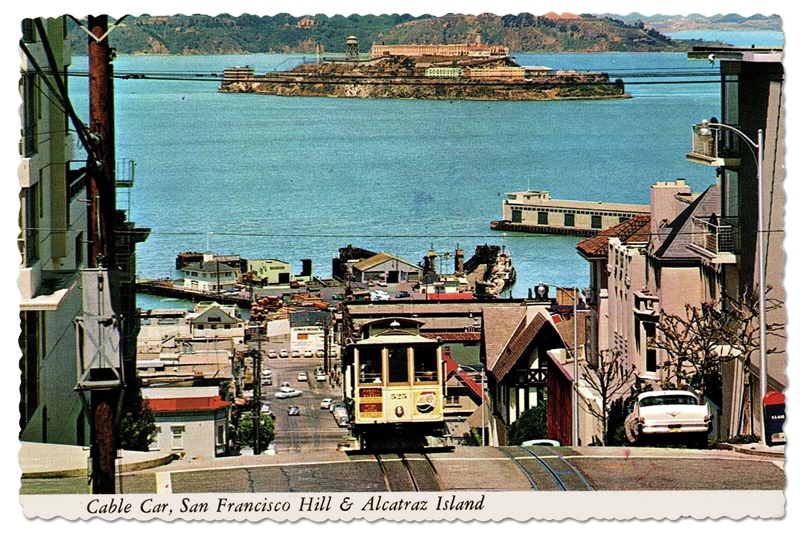 Vintage color postcard showing a cable car descending a steep San Francisco street toward the bay, with Alcatraz Island in the distance.