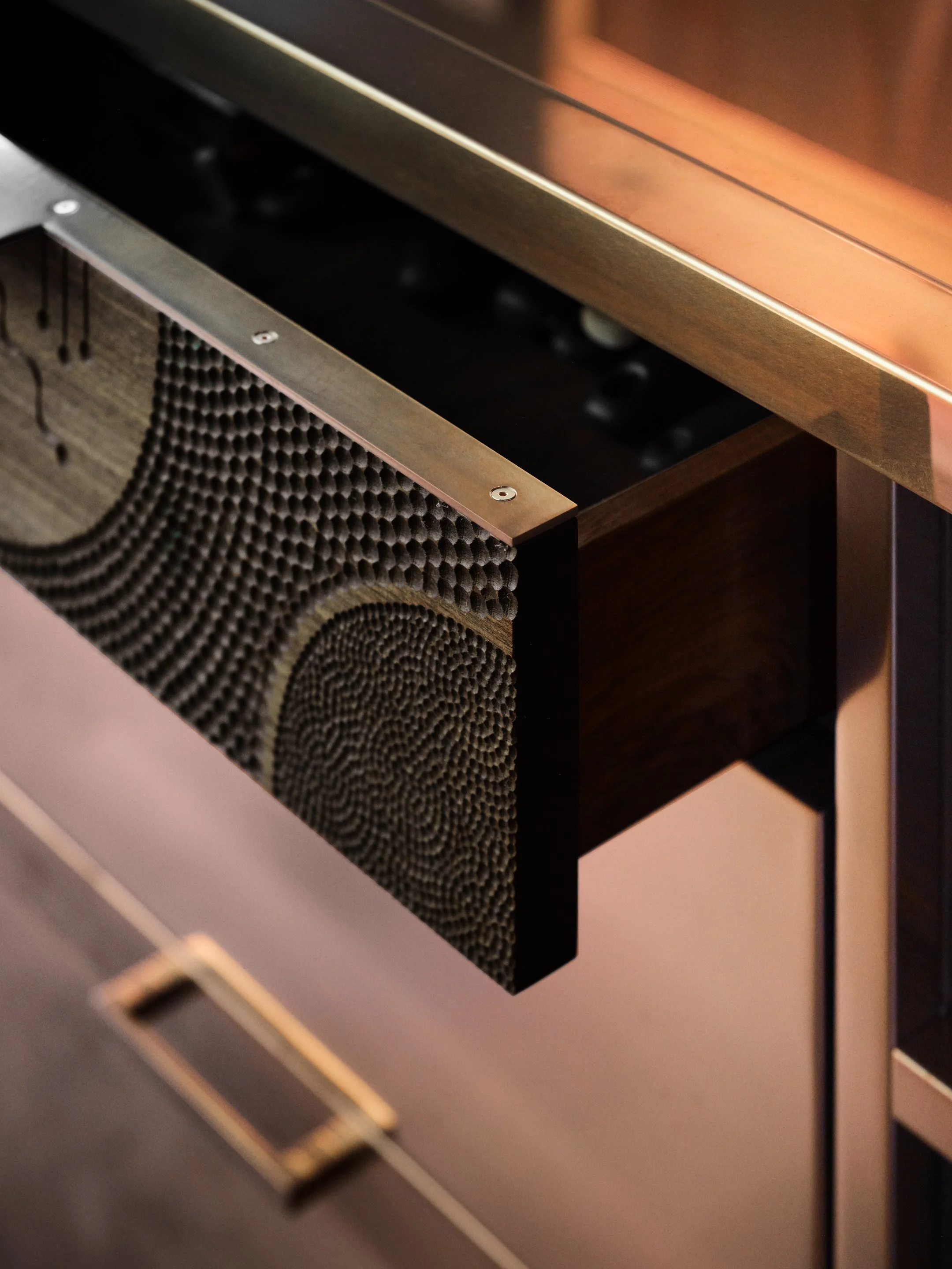 Close-up of copper island and open drawer featuring a detailed circular geometric design on the front.