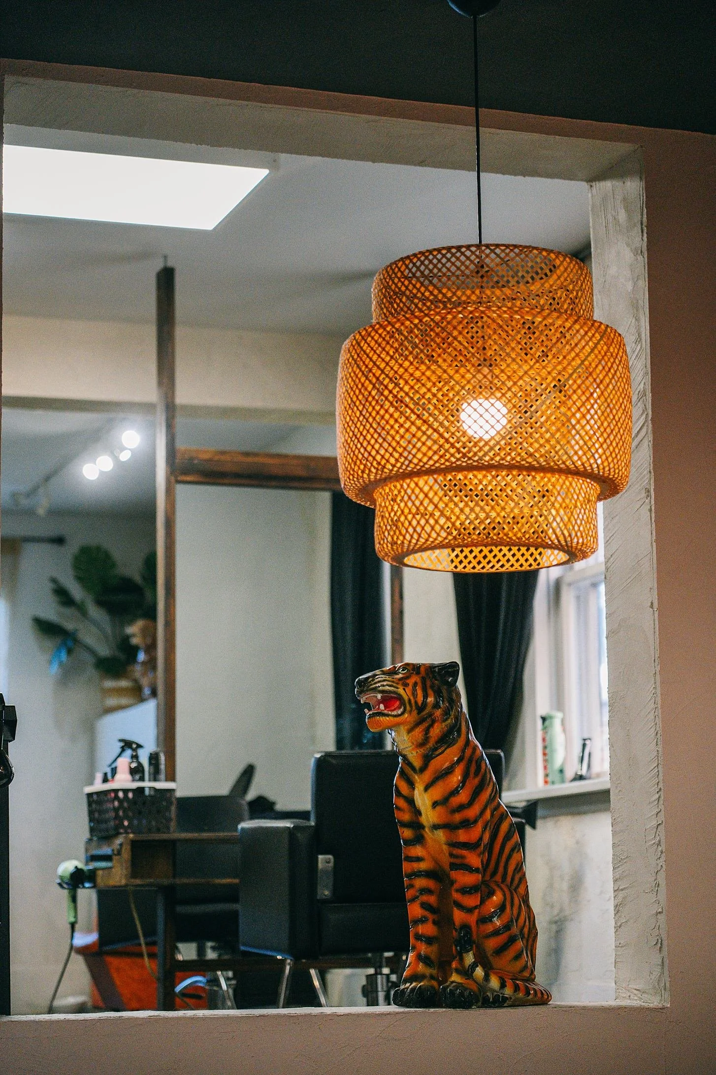 Decorative tiger figurine placed on a counter with a woven pendant light hanging above in an indoor setting.