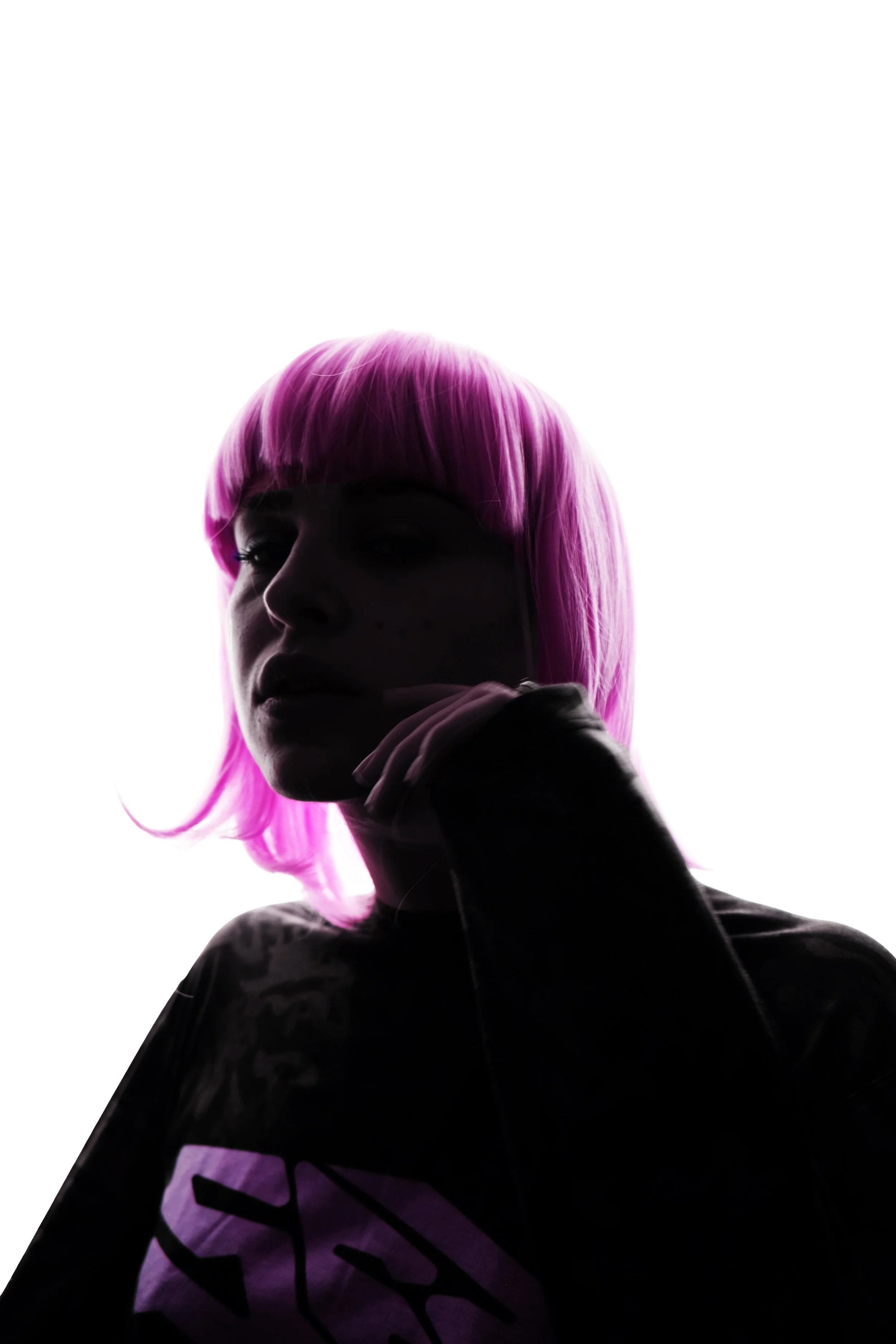 A person with bright pink hair, partially visible, touching their chin with their hand, wearing a dark top with a purple pattern and a purple Nike logo.