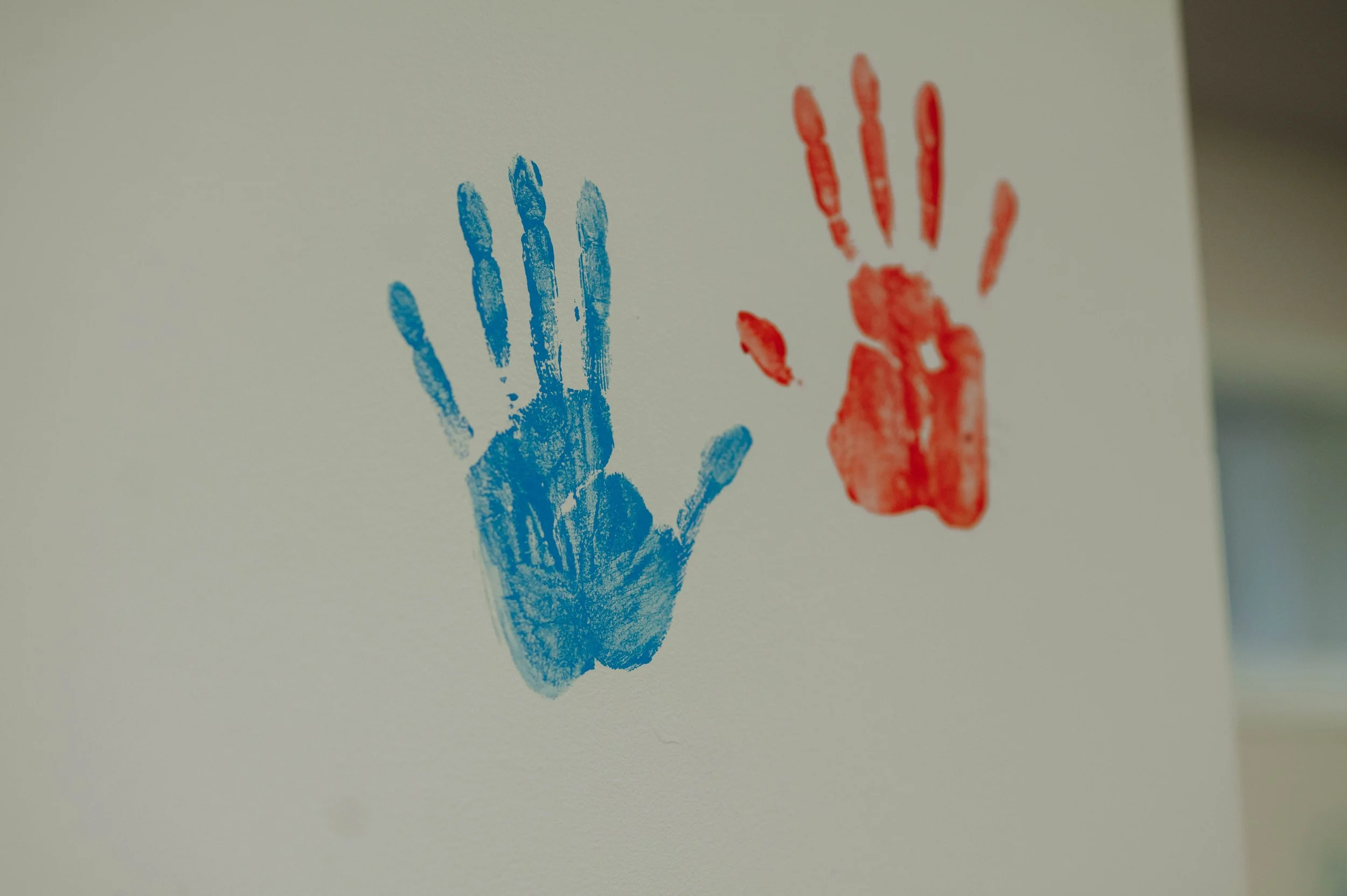 Close-up of two handprints, one in blue and one in red, on a white wall in the Children's Ministry at Bethel Church near Carstairs AB.