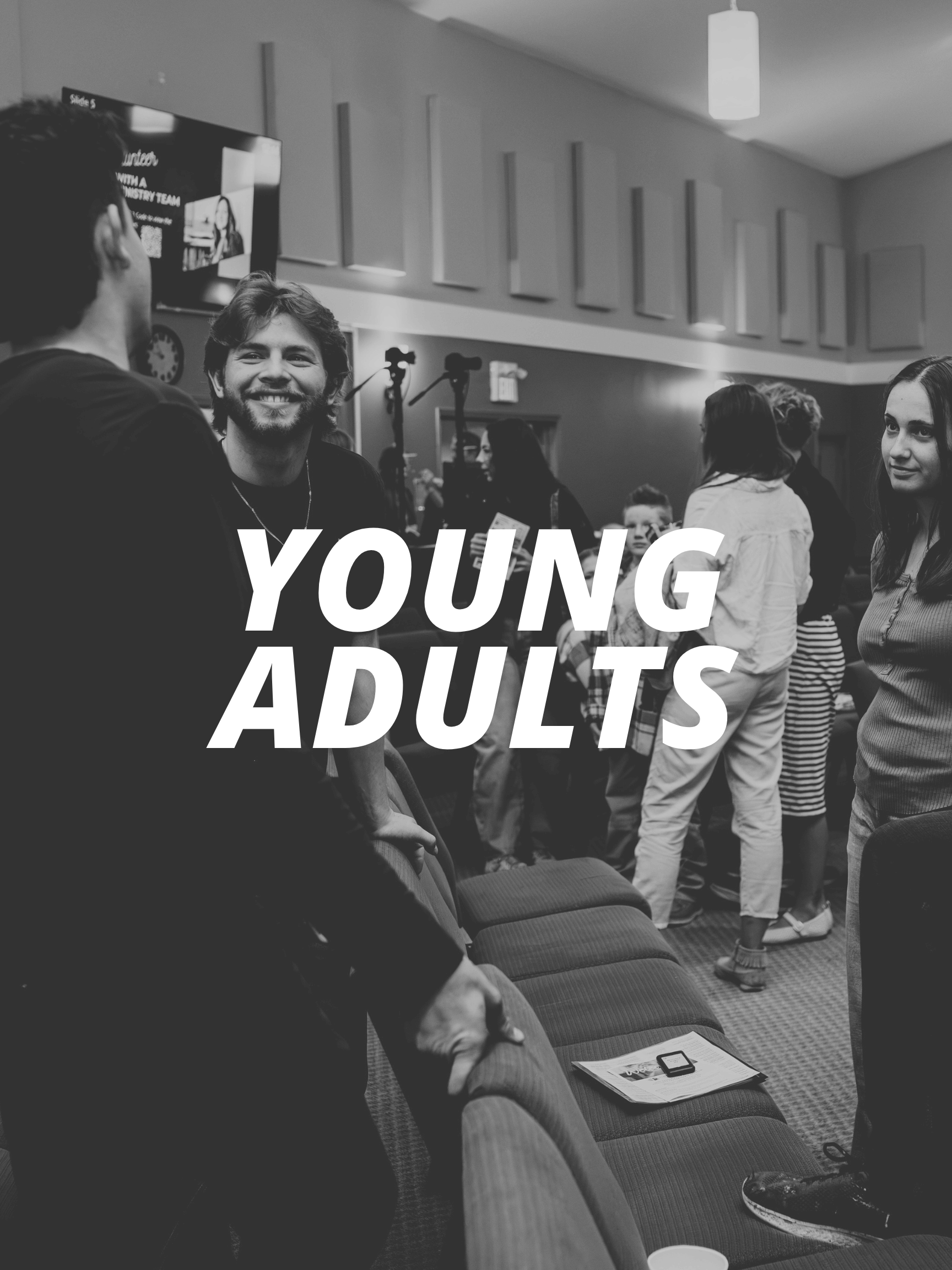 People gathered and conversing indoors with large windows, some holding drinks, with bold text reading 'YOUNG ADULTS' overlaid on the image.