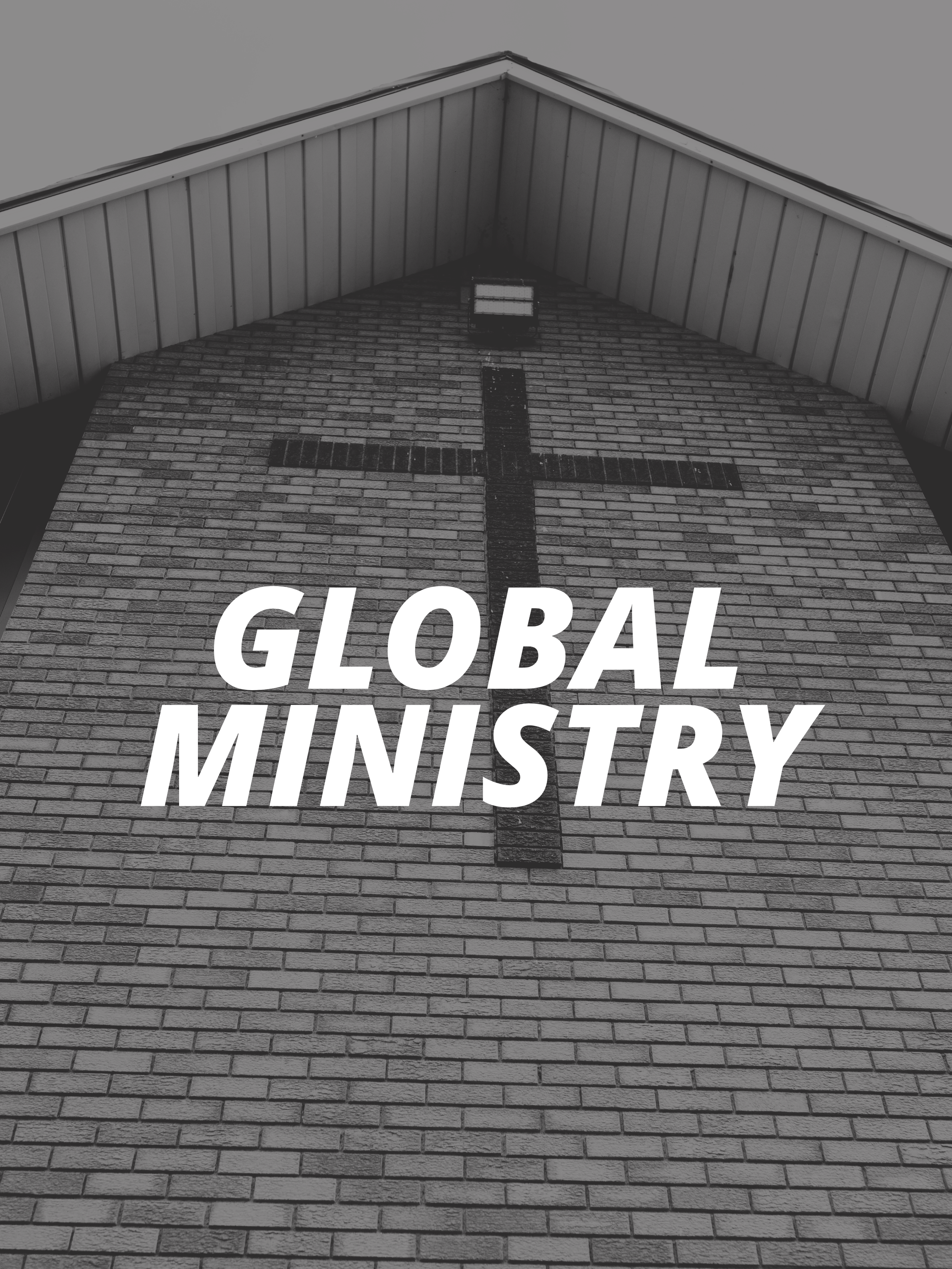 Close-up of a brick church wall with a black cross and part of a word reading 'GLOBAL' on it, with the roof's eaves and a light fixture visible.