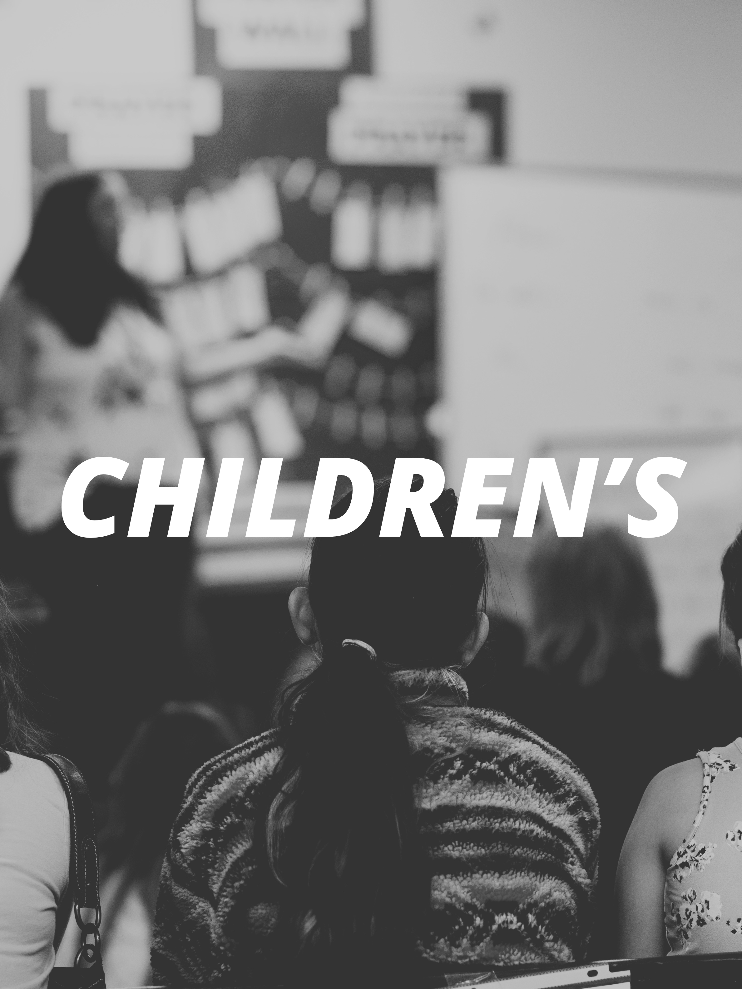 Black and white photo of children sitting in a classroom with a teacher at the front, who is pointing at a blackboard with white posters, with the word 'CHILDREN'S' overlaid in large letters.