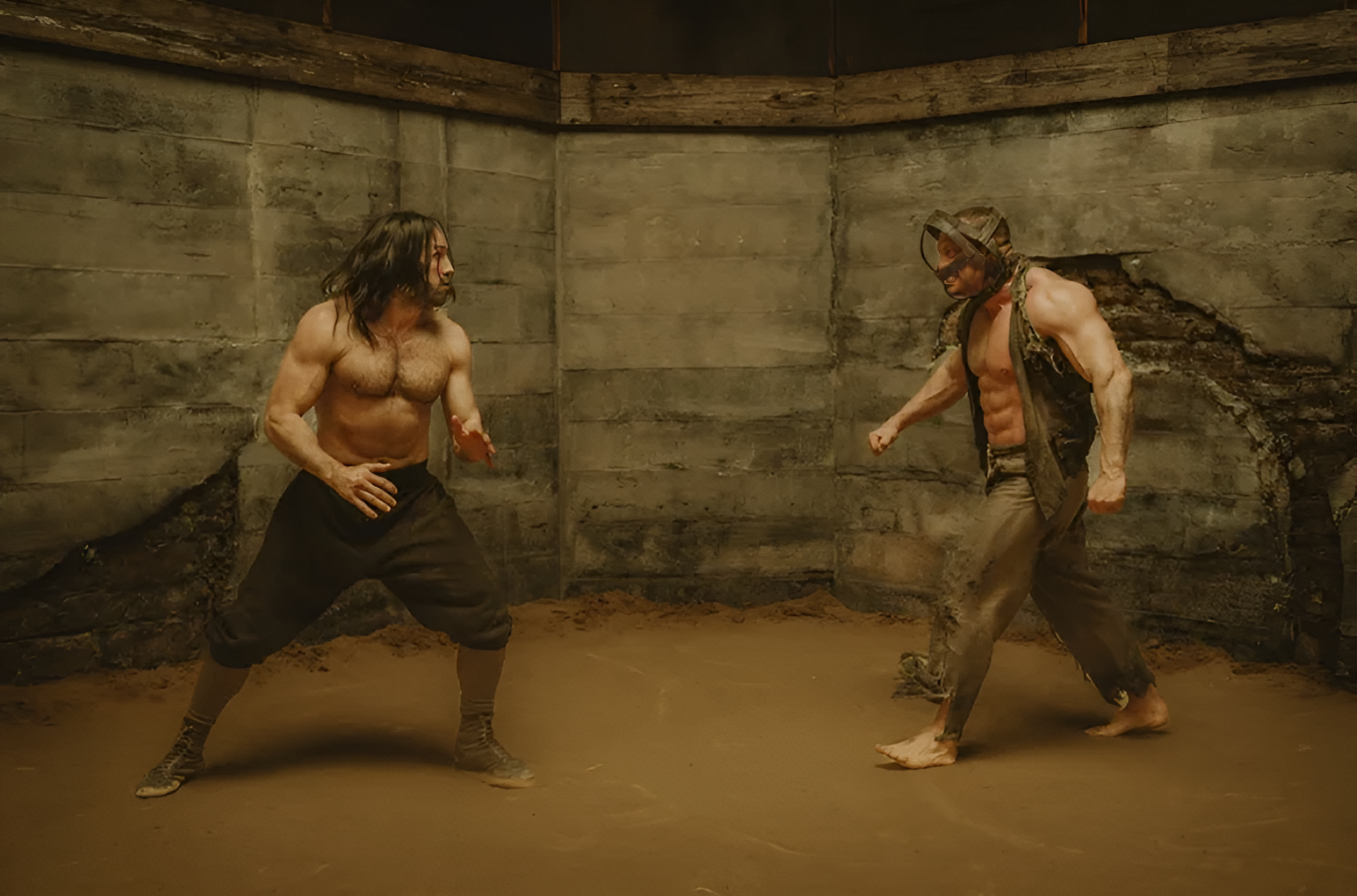 Two shirtless men with muscular physiques and long hair, wearing pants, are fighting in a dirt-filled, enclosed area with concrete walls. One of them is wearing a camouflage vest and a helmet. They are in aggressive stances, fists clenched, and appear to be engaged in combat.