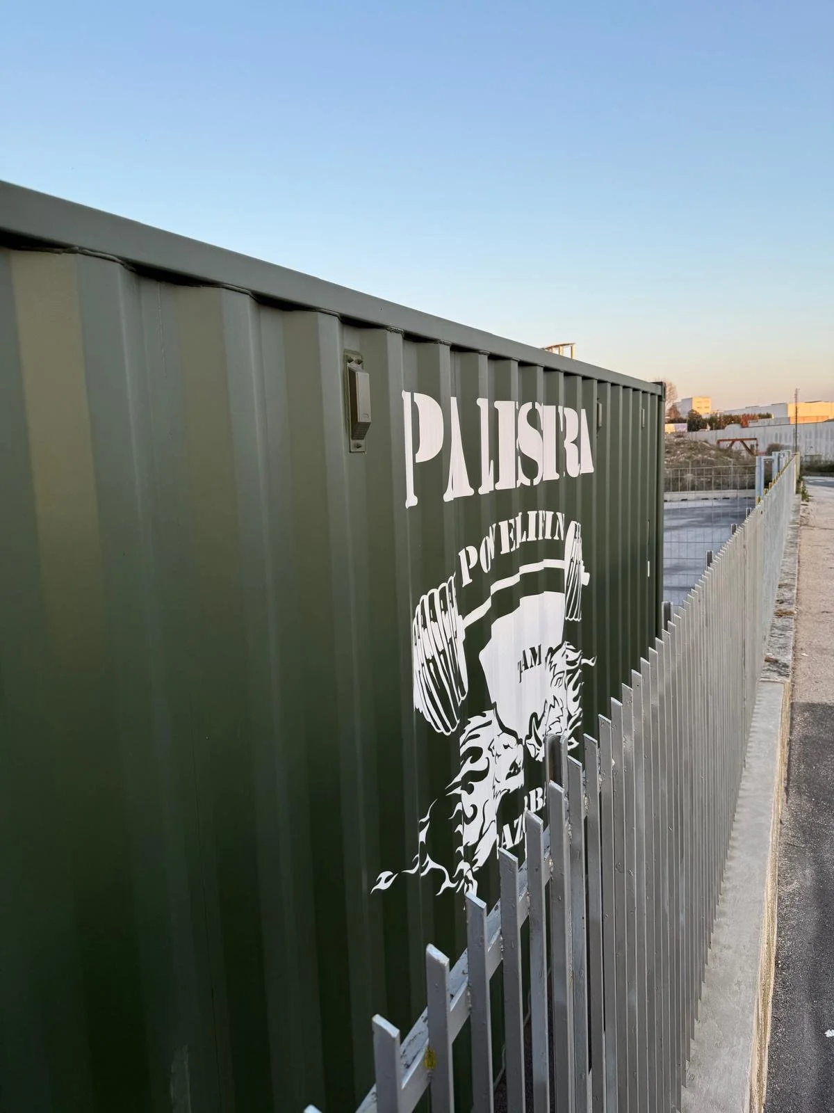 Recinzione con logo di palestra di sollevamento pesi e scritte in caratteri curvi.