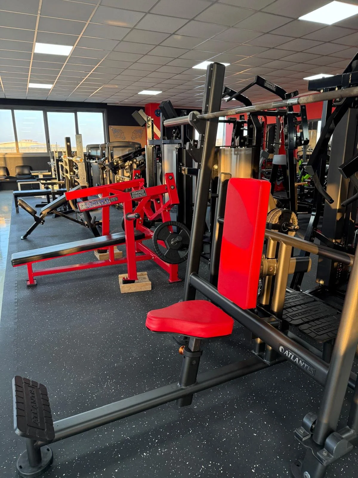Palestra con attrezzi per esercizi di forza e cardio, sedie nere e luci da soffitto