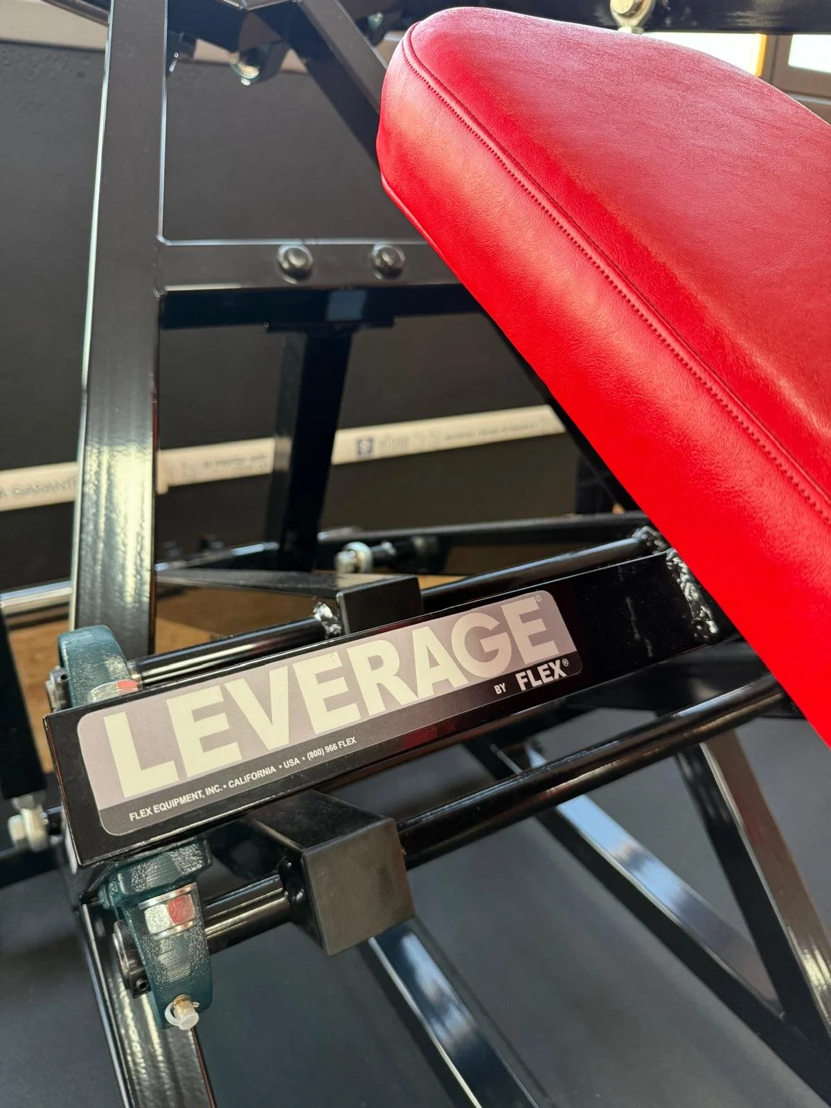 Istallazione di un attrezzo da ginnastica della marca LEVERAGE di Flex, con una panca rossa e struttura nera in un centro fitness.