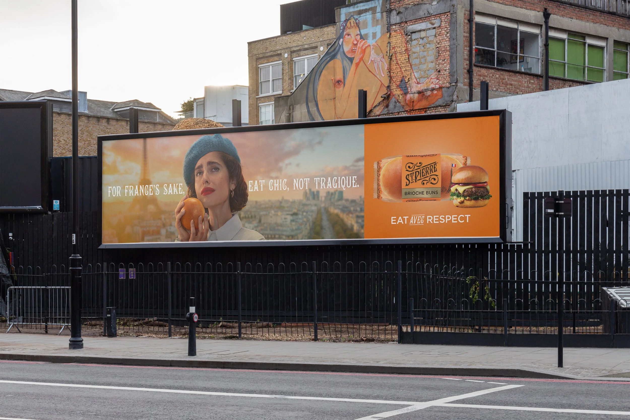 A large billboard on a black fence displays an advertisement featuring a woman with short hair, wearing a blue beret and red lipstick, holding an orange, with the Eiffel Tower in the background. Text on the billboard reads: "For France's sake, eat ch