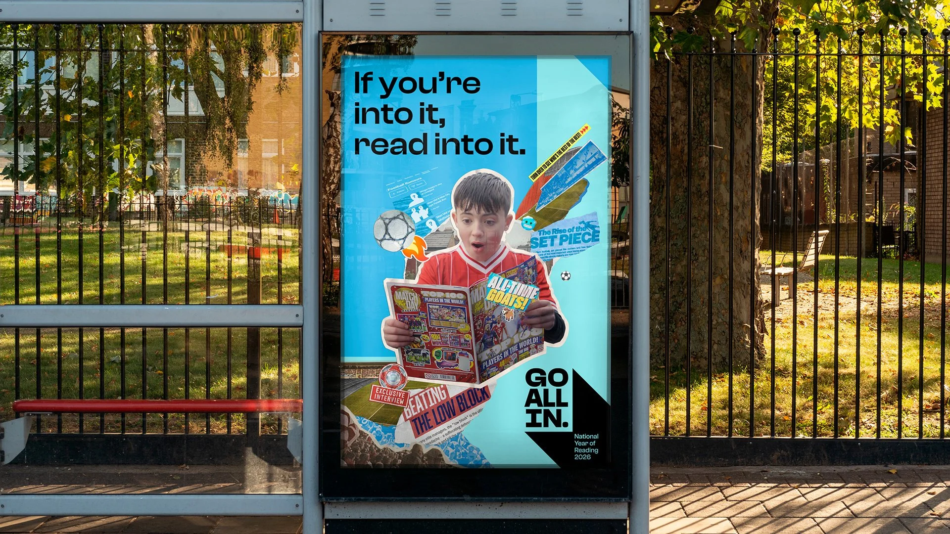 Poster on a bus stop shelter featuring a surprised young boy reading a magazine, with sports and comic-themed graphics, including phrases like 'If you're into it, read into it' and 'Go All In.'