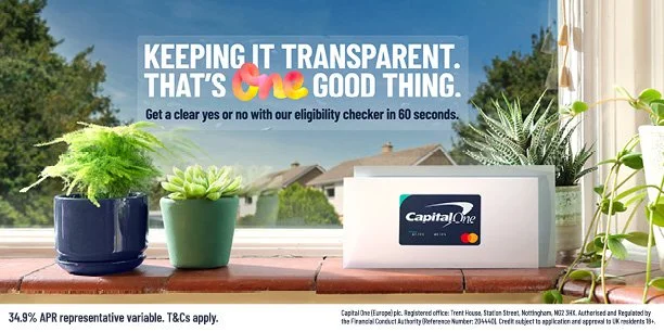 A window sill with potted plants, a white Capital One credit card, and a background of houses and trees outside. The top text reads 'Keeping it transparent. That's one good thing.'