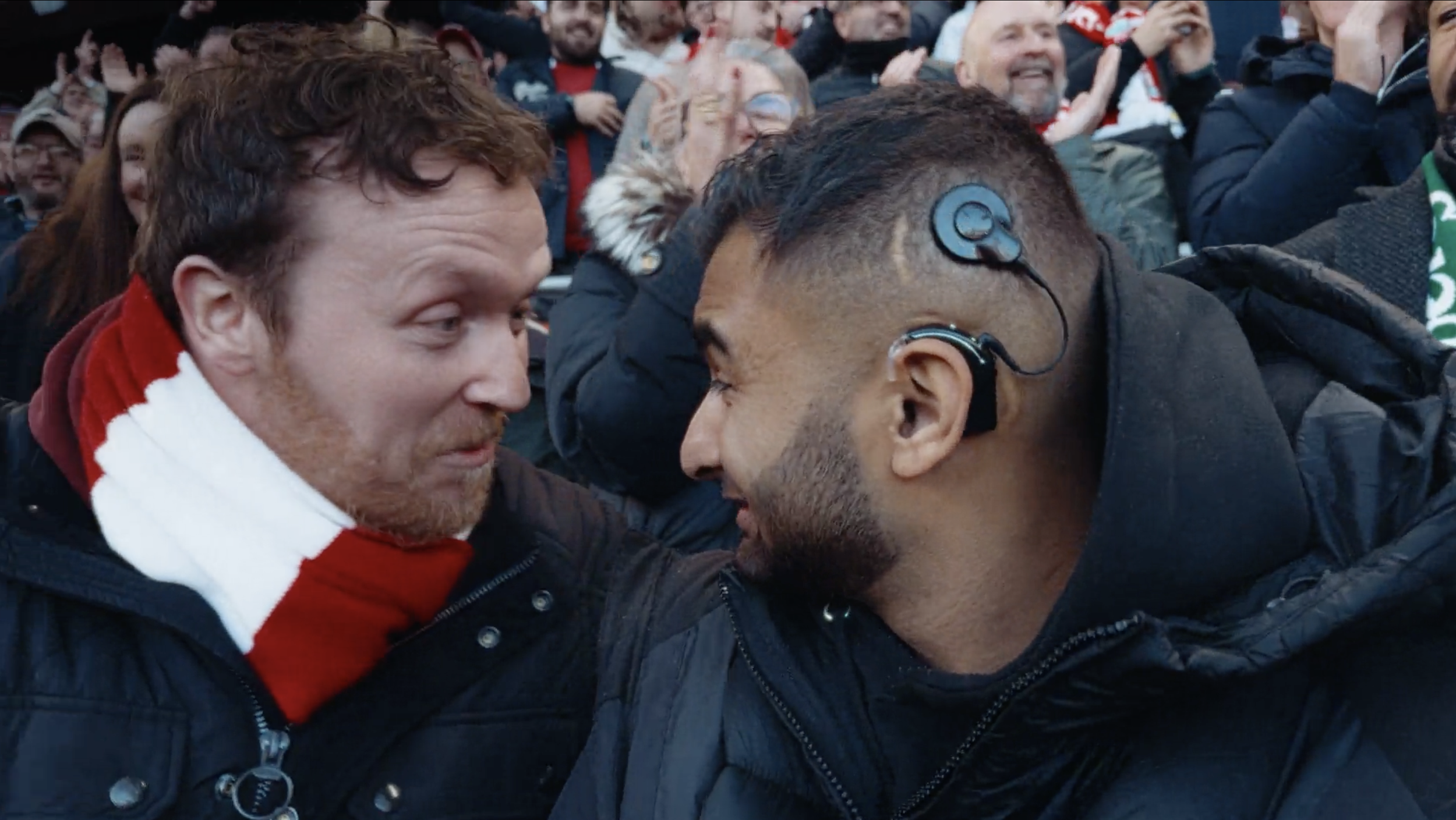 Two men are face to face, in close proximity, with their foreheads touching during a conflict or argument, surrounded by a crowd of people.