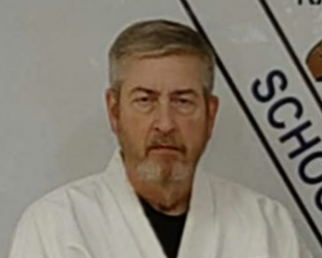 A man with gray hair and beard in a white martial arts uniform