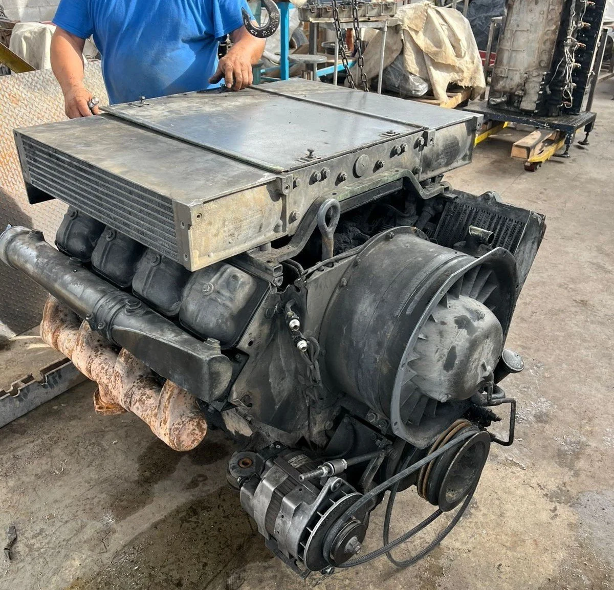 Motor de automóvil grande en un taller, con herramientas y piezas en el fondo.