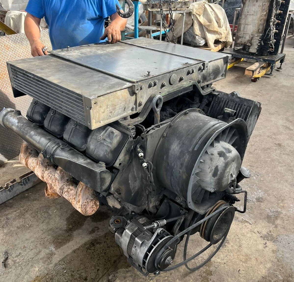 Motor de automóvil en un taller, con un intercooler instalado y varias piezas y herramientas en el fondo.
