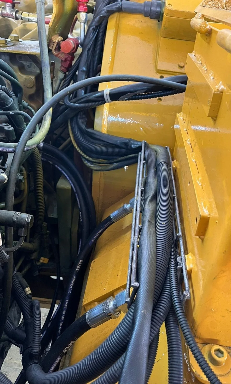 Múltiples cables y mangueras en una maquinaria amarilla, organizados y asegurados en un compartimiento.