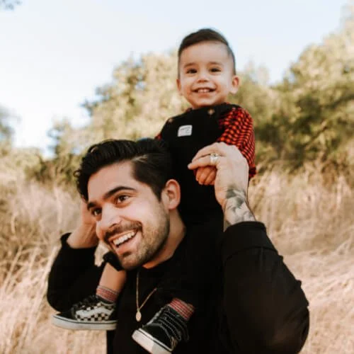 A small autistic boy sits on his dad's shoulders