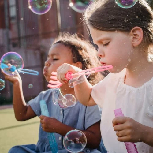 Two girls socialize, blowing bubbles
