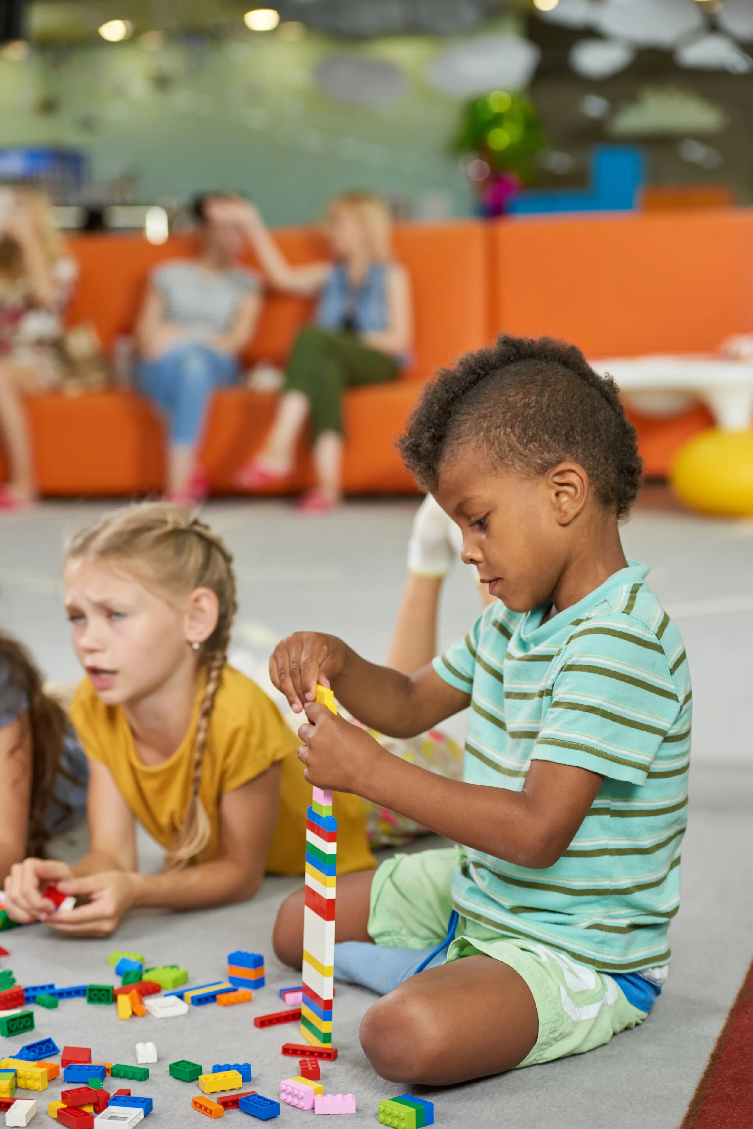 Preschool age children playing with blocks on floor.