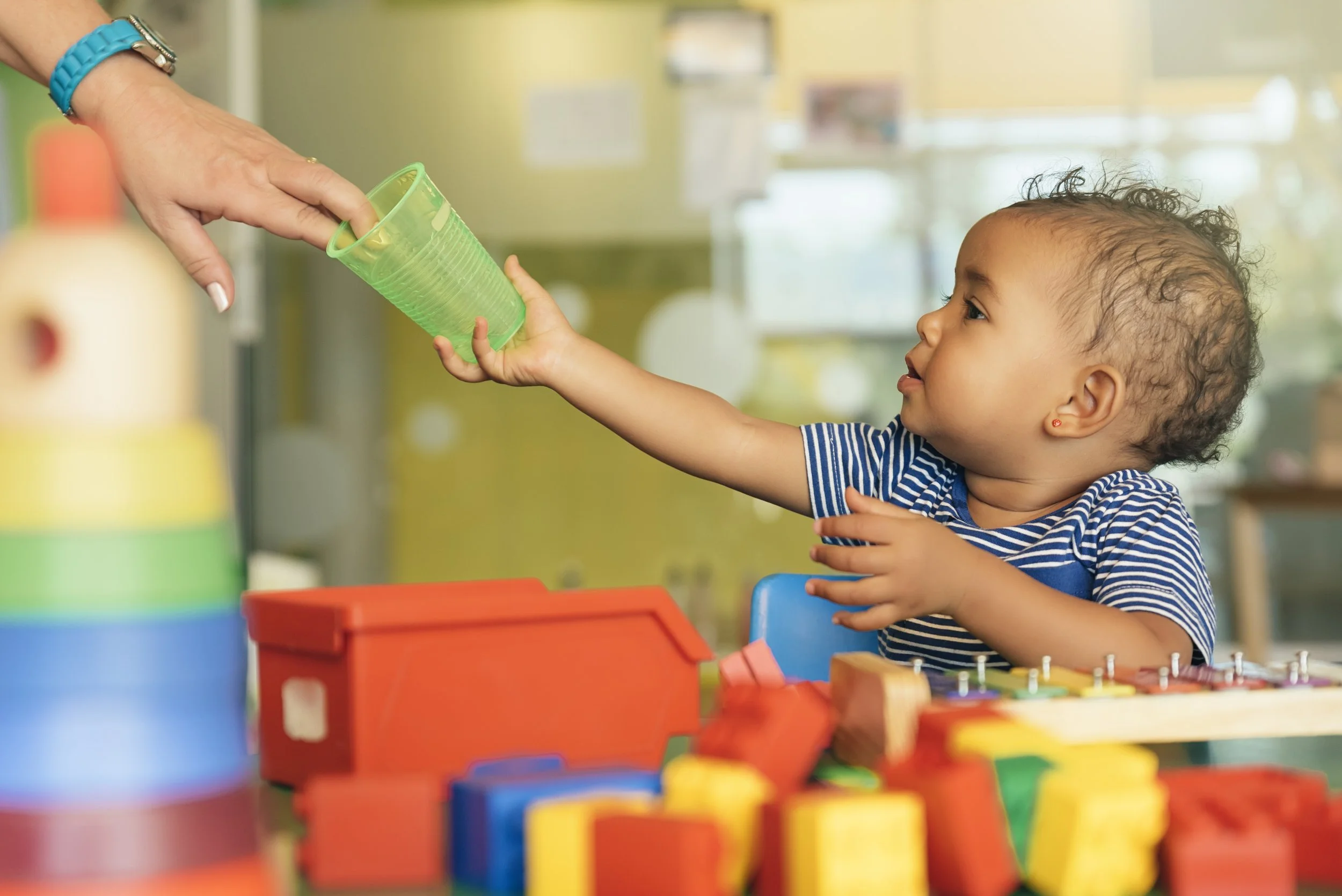Infant child reaching for cup.