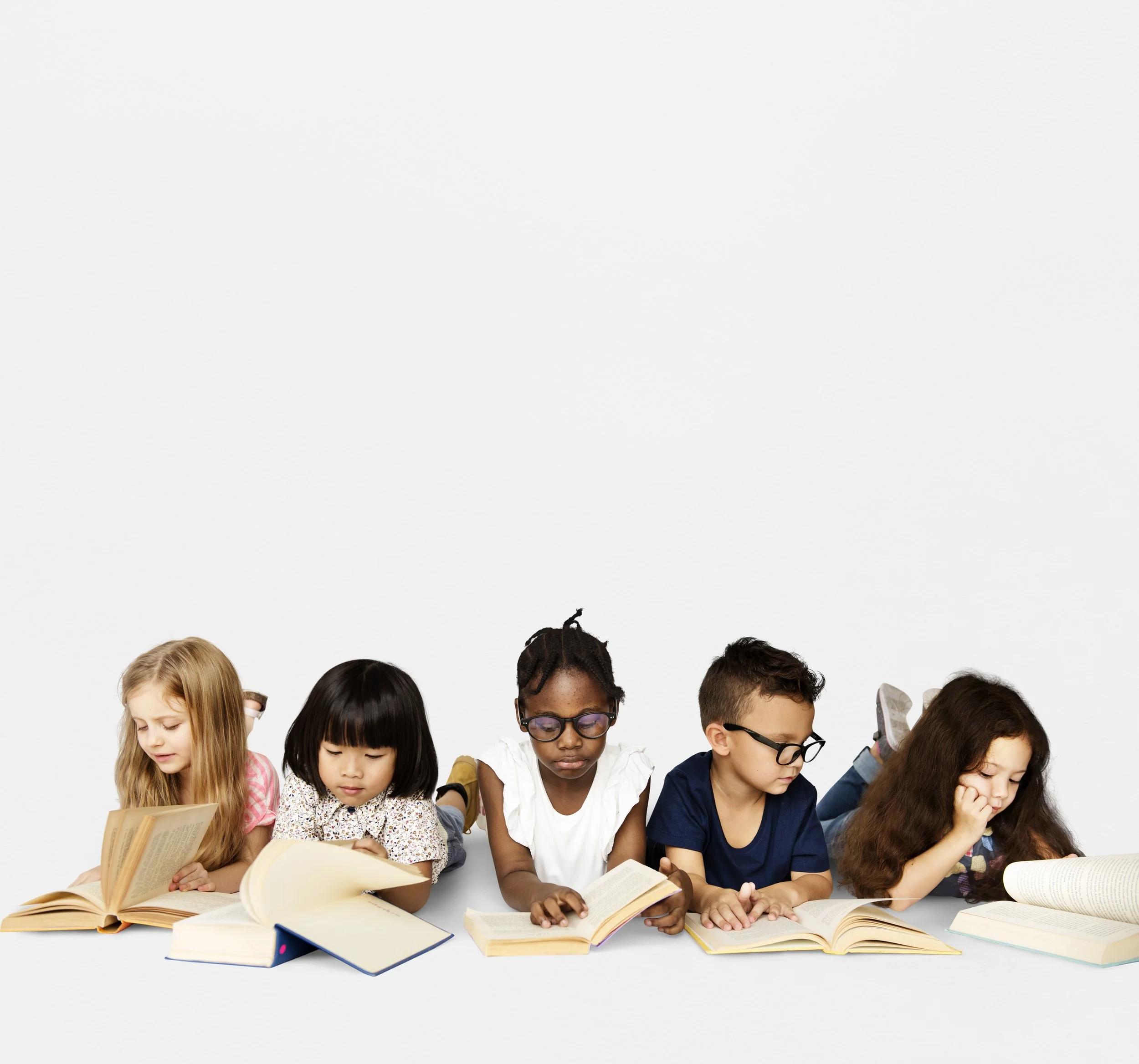 Group of preschool age children sitting at a table reading books in front of a plain white background.