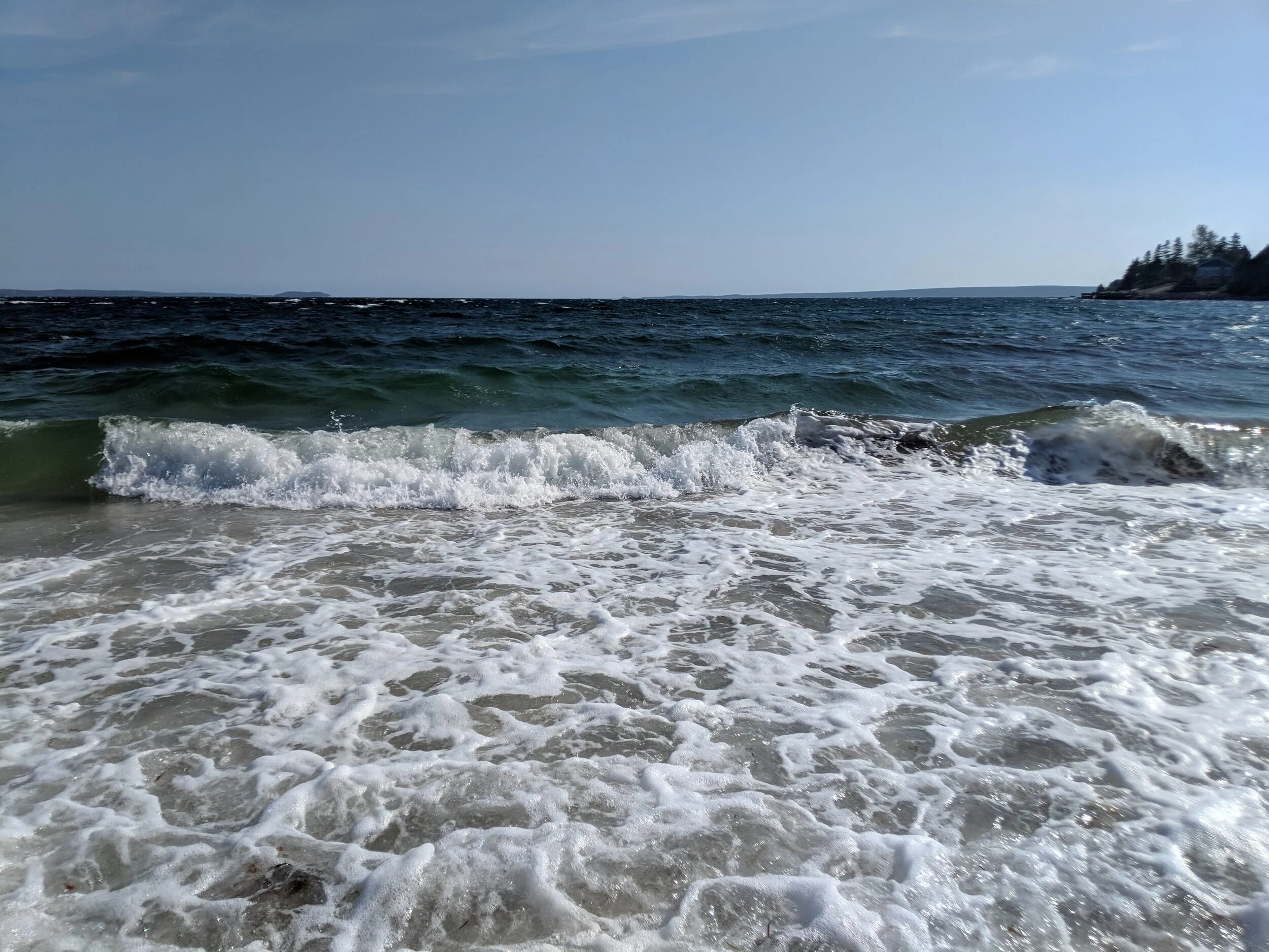 A wave breaking and running up the sand on a Nova Scotia beach.