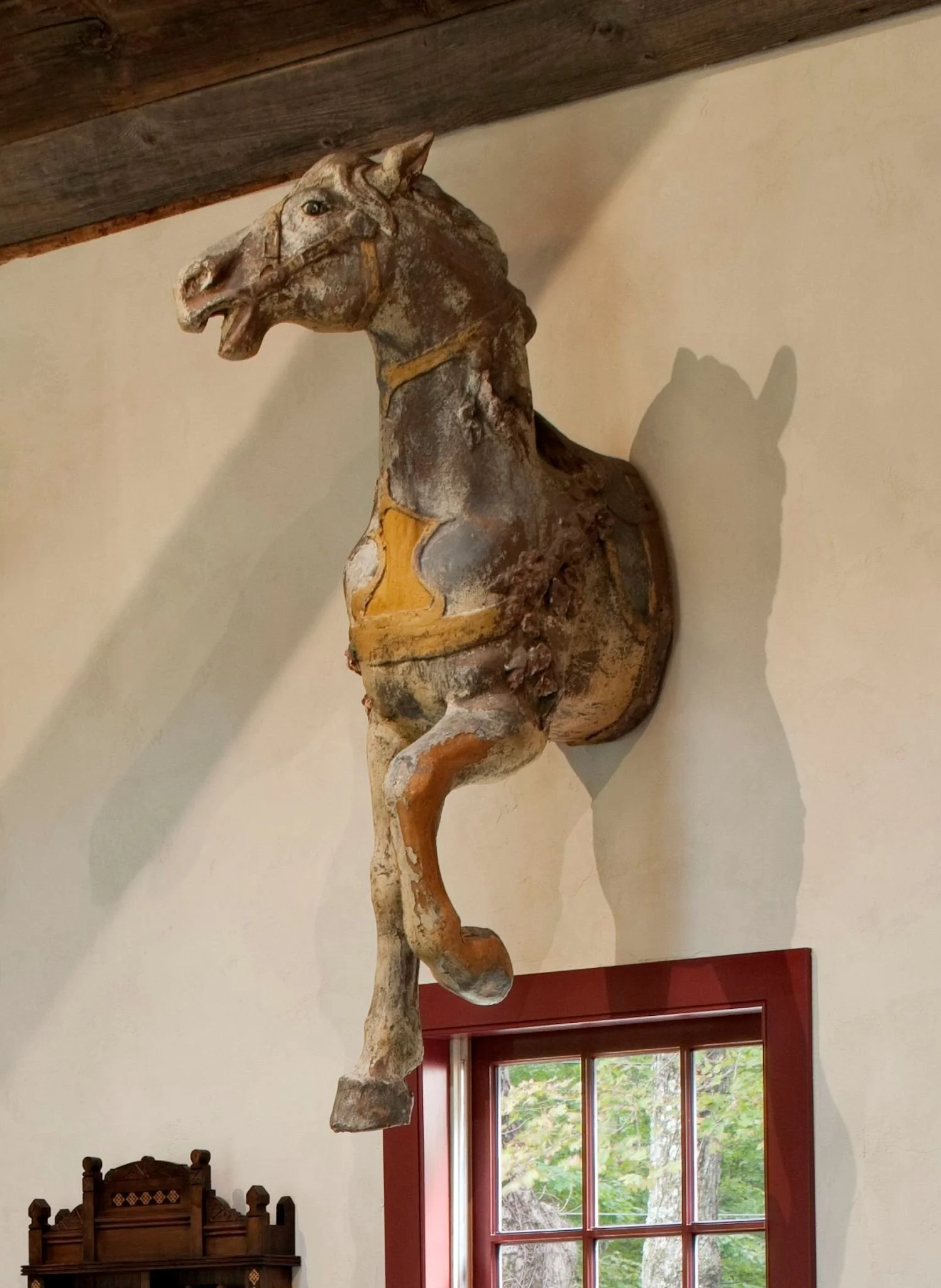 An early 20th century carousel horse in original paint, mounted on the wall of a converted antique barn.