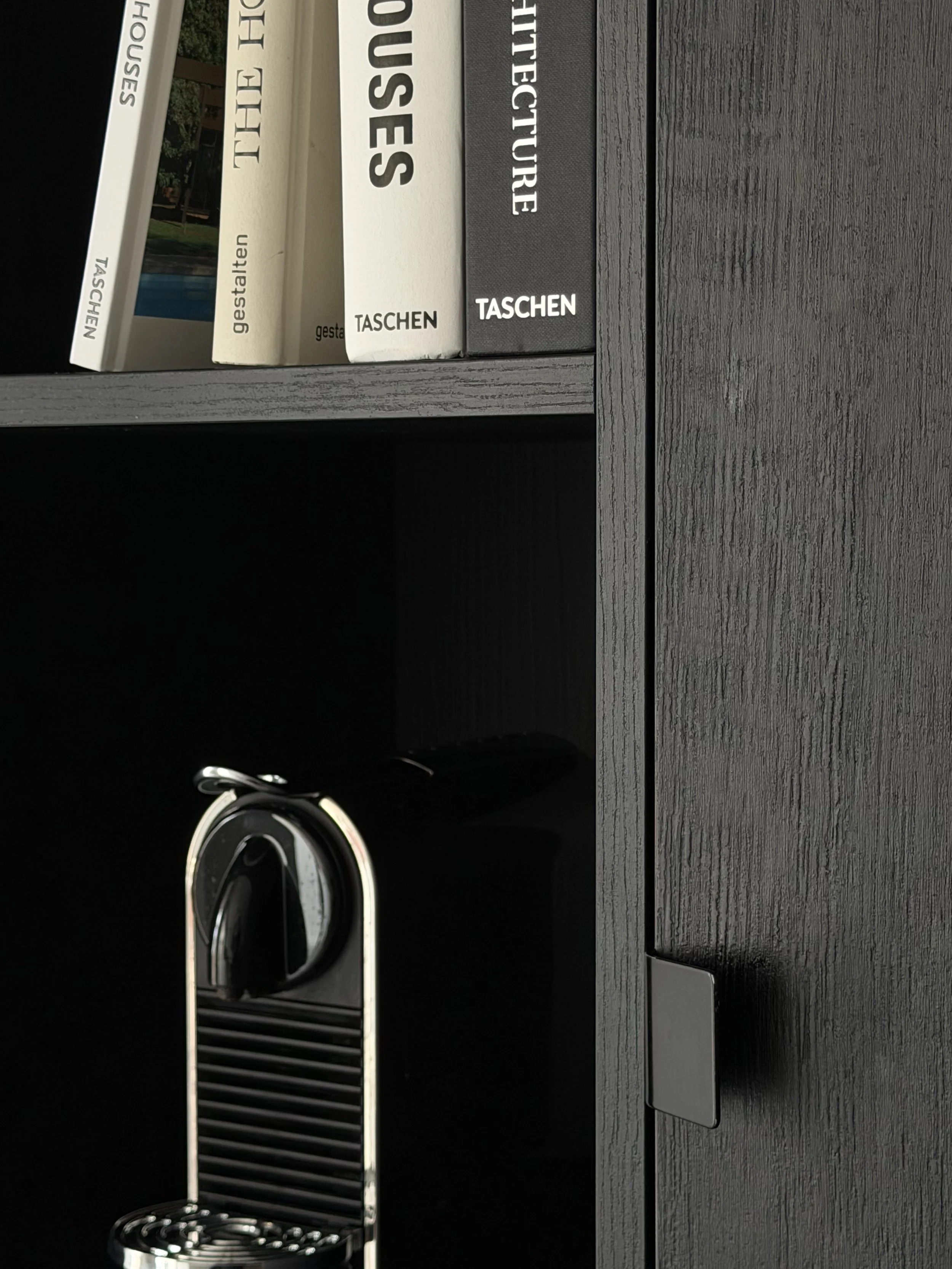 KEUKENKAST IN ZWARTE EIKFINEER MET KOFFIEZET EN BOEKEN EN EEN CLOSE UP VAN DE KASTGREEP DOOR MAV INTERIOR ARCHITECTURE
