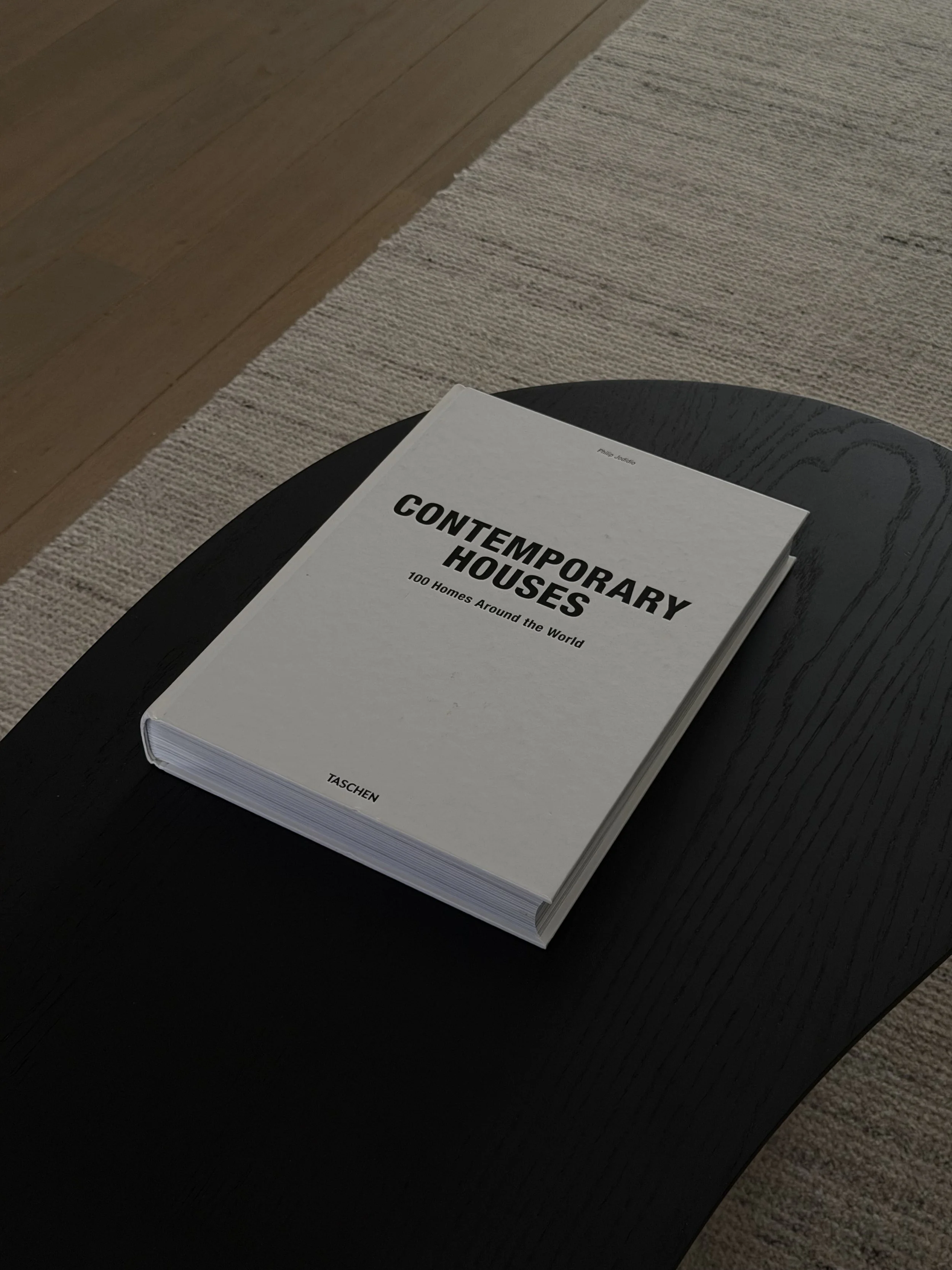 LICHTE EIKEN PARKET MET BEIGE TAPIJT EN ZWARTE TAFEL MOET BOEK VAN HET MERK TASCHEN DOOR MAV INTERIOR ARCHITECTURE