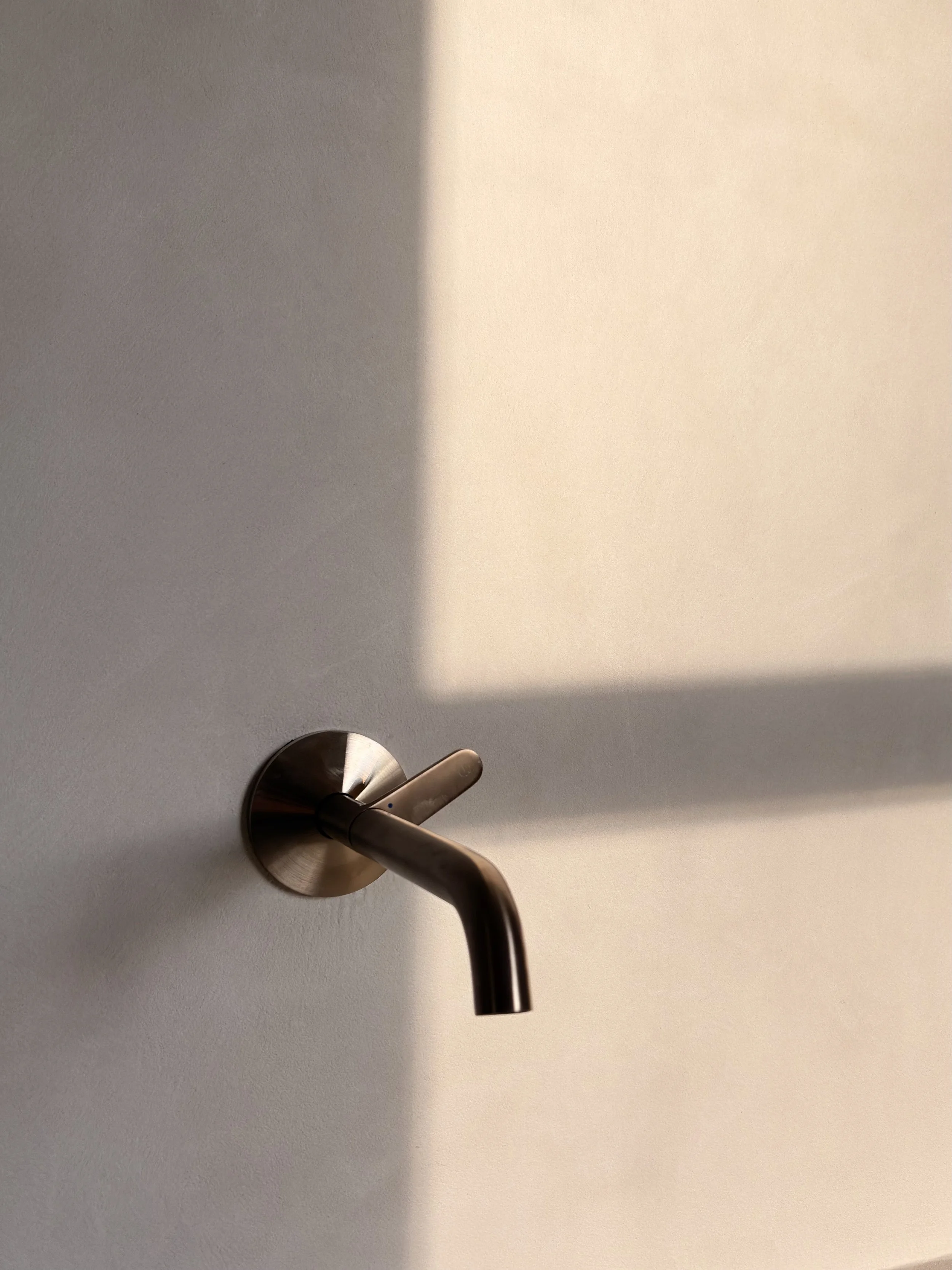 A modern metal door handle mounted on a white door with a shadow cast on the door surface.