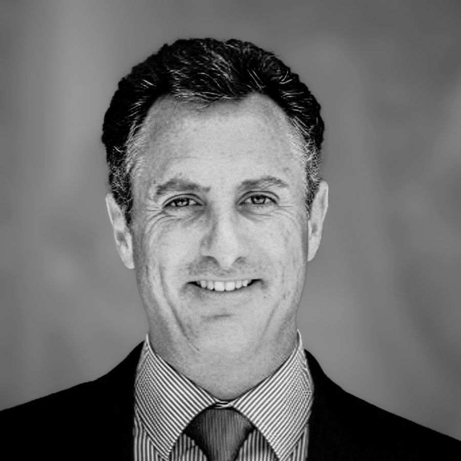 A black-and-white portrait of a smiling man wearing a suit, tie, and shirt.