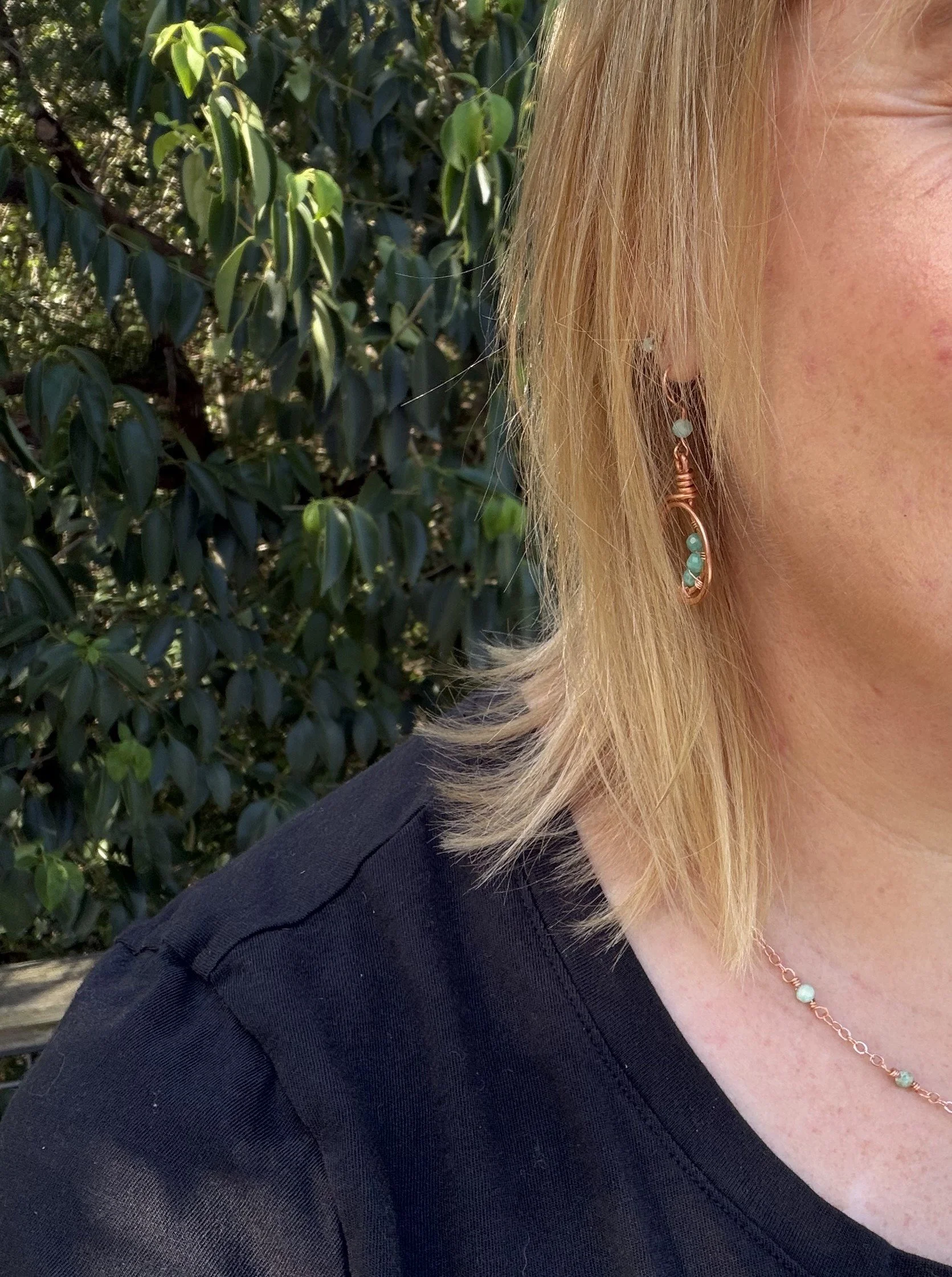 woman wearing handmade hammered copper double loop earrings with wire-woven amazonite beads