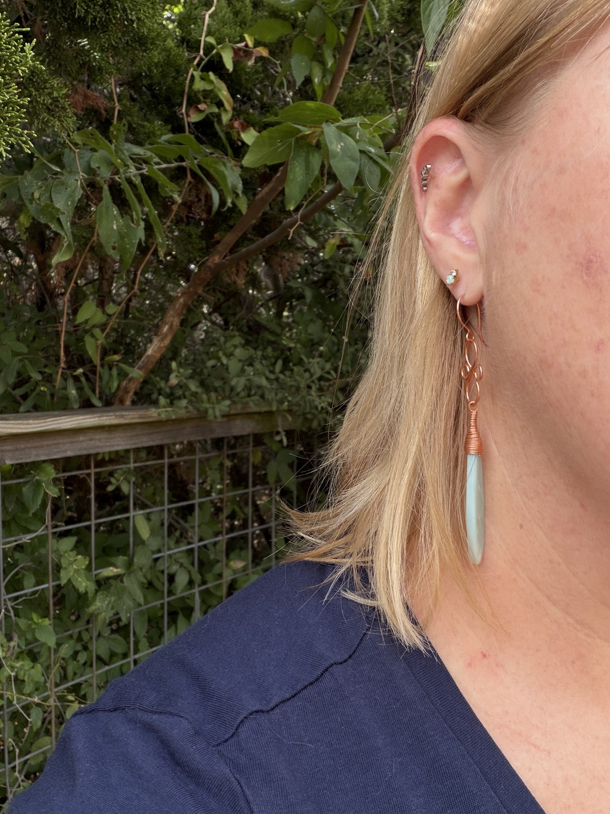 WOMAN WEARING handmade calcite copper wire wrapped teardrop earrings with ornate copper knotwork link