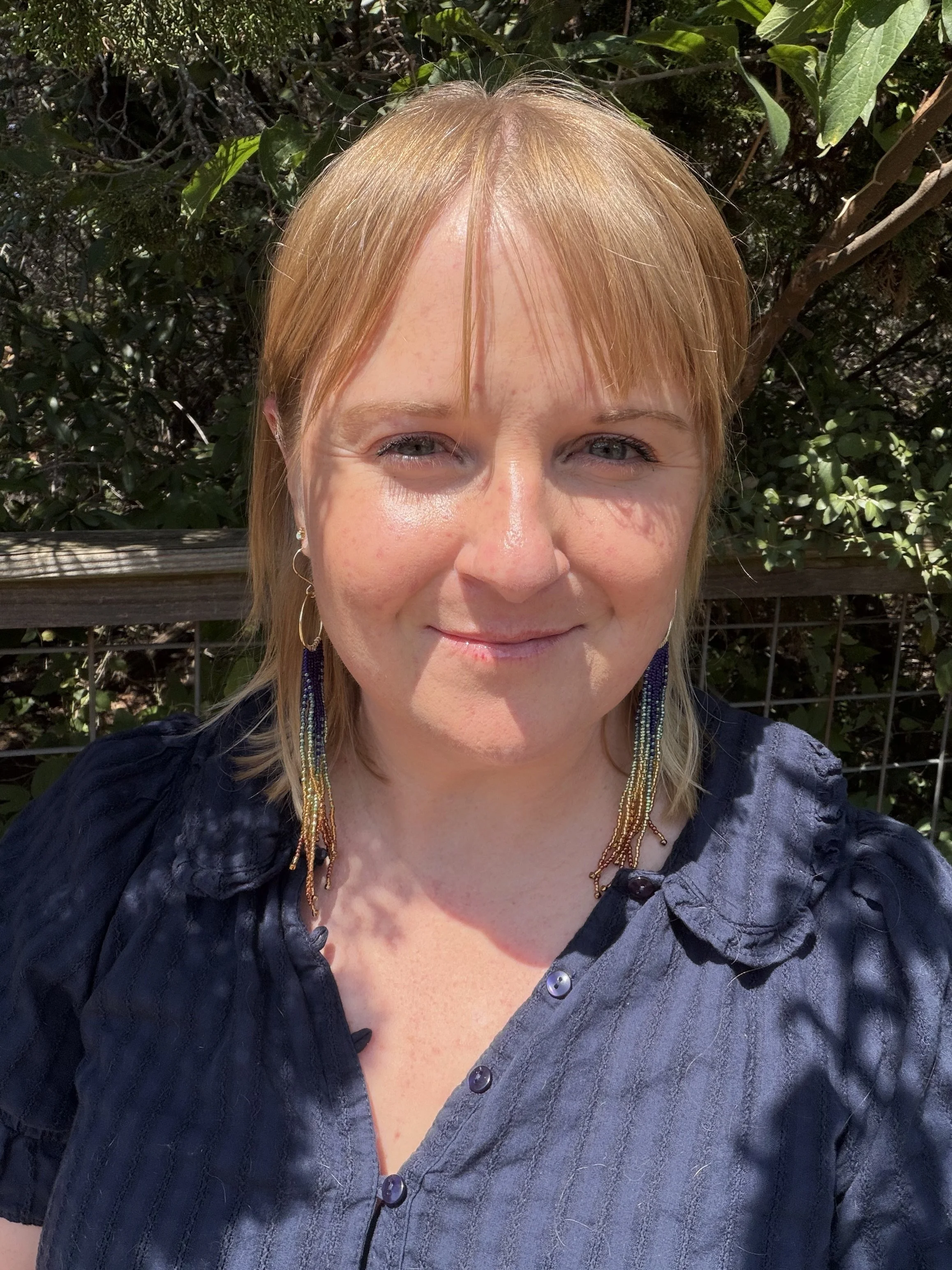 woman wearing handmade seed bead fringe earrings on gold hoops, navy teal gold and copper ombre, gold-filled ear wire
