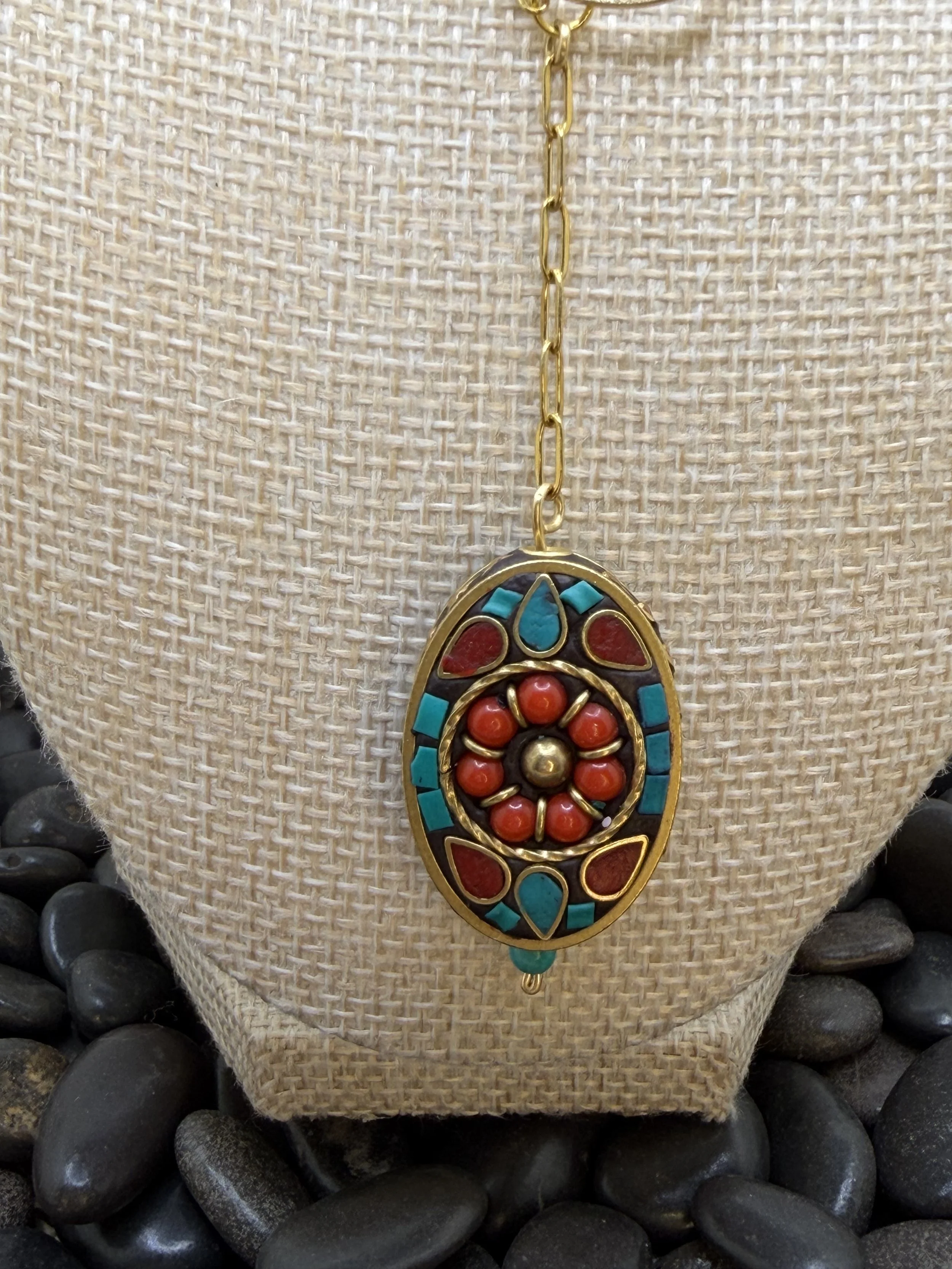 Handmade asymmetrical necklace with a Tibetan brass coral and turquoise howlite inlay pendant, red coral and amazonite beads, and a gold-toned paperclip chain