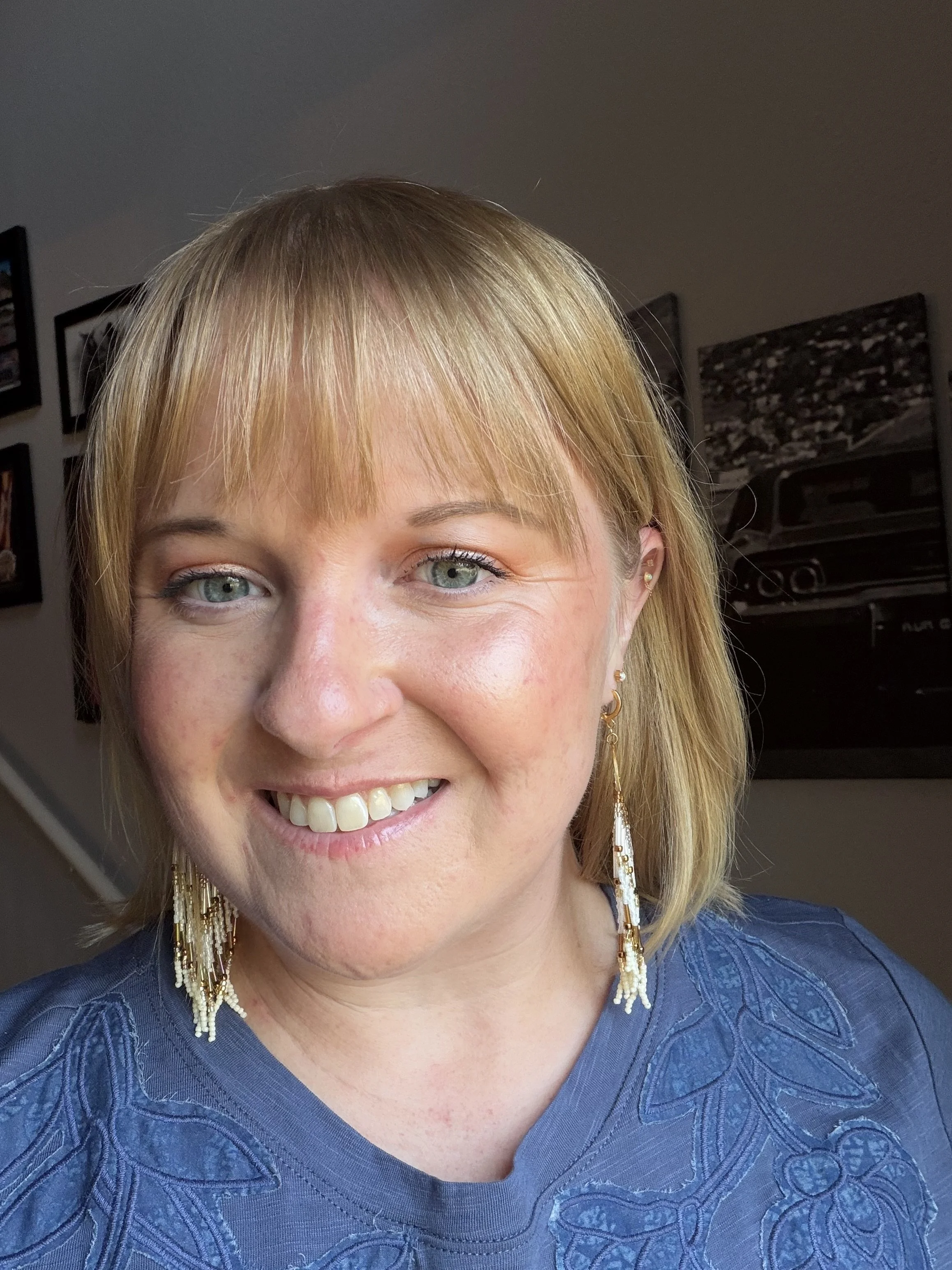 woman wearing handmade seed bead fringe earrings with brass moon phase charm and cream bronze gold beading