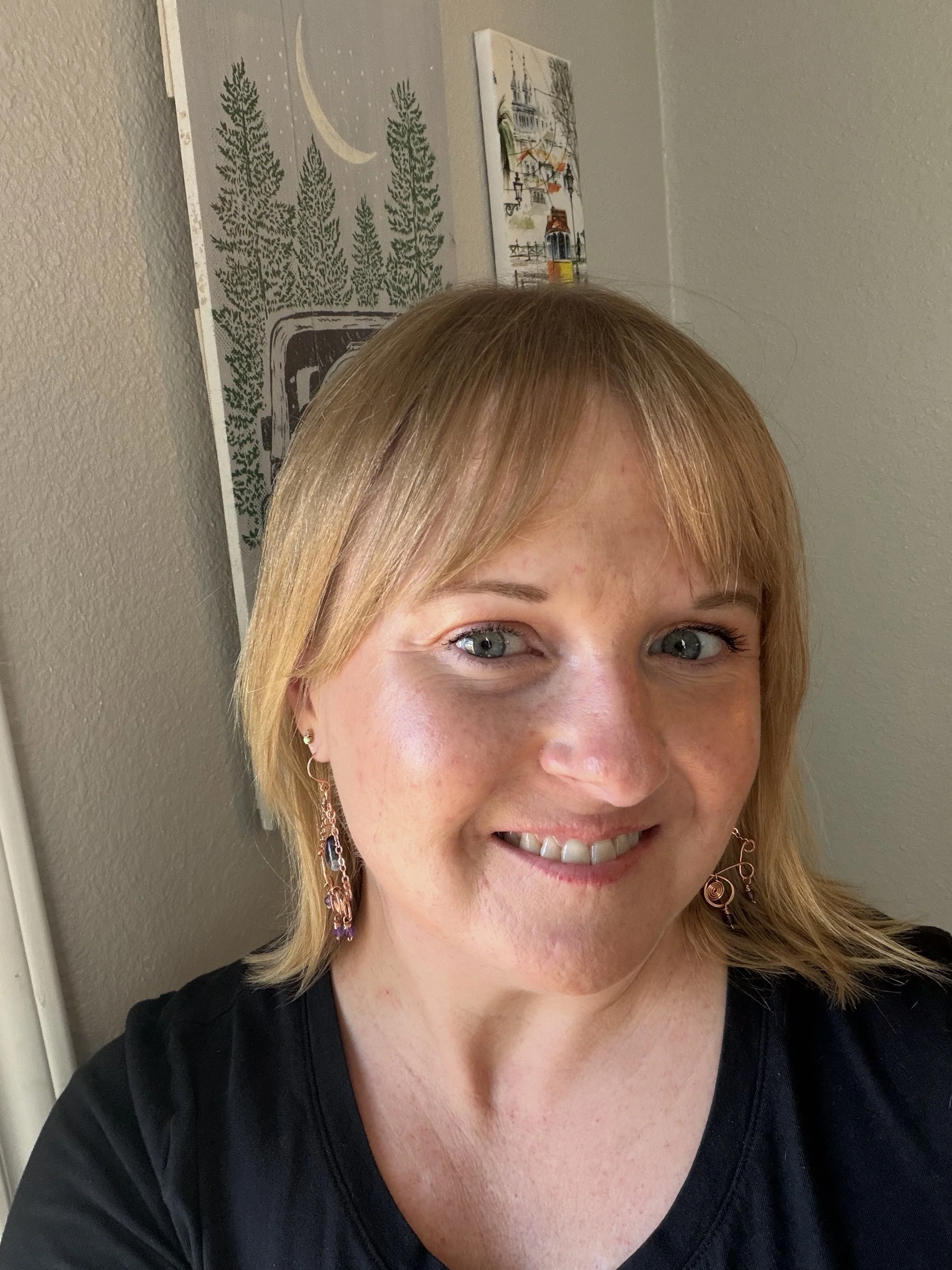 woman wearing Handmade copper chandelier earring worn on an ear, with scroll connectors, copper chains, a center spiral, an amethyst teardrop, and three small faceted amethyst beads.