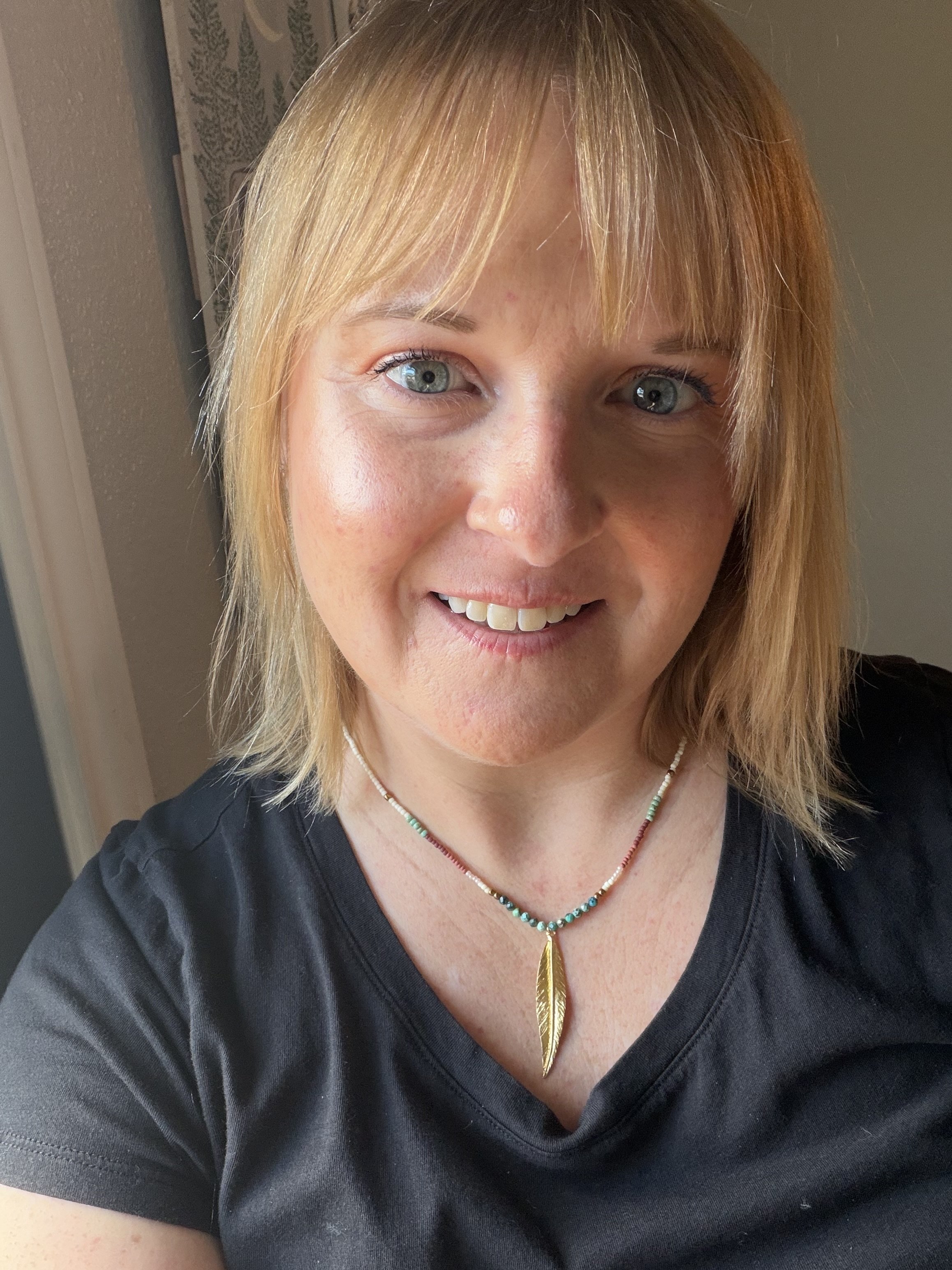 woman wearing handmade seed bead necklace with turquoise beads and gold stainless steel feather pendant