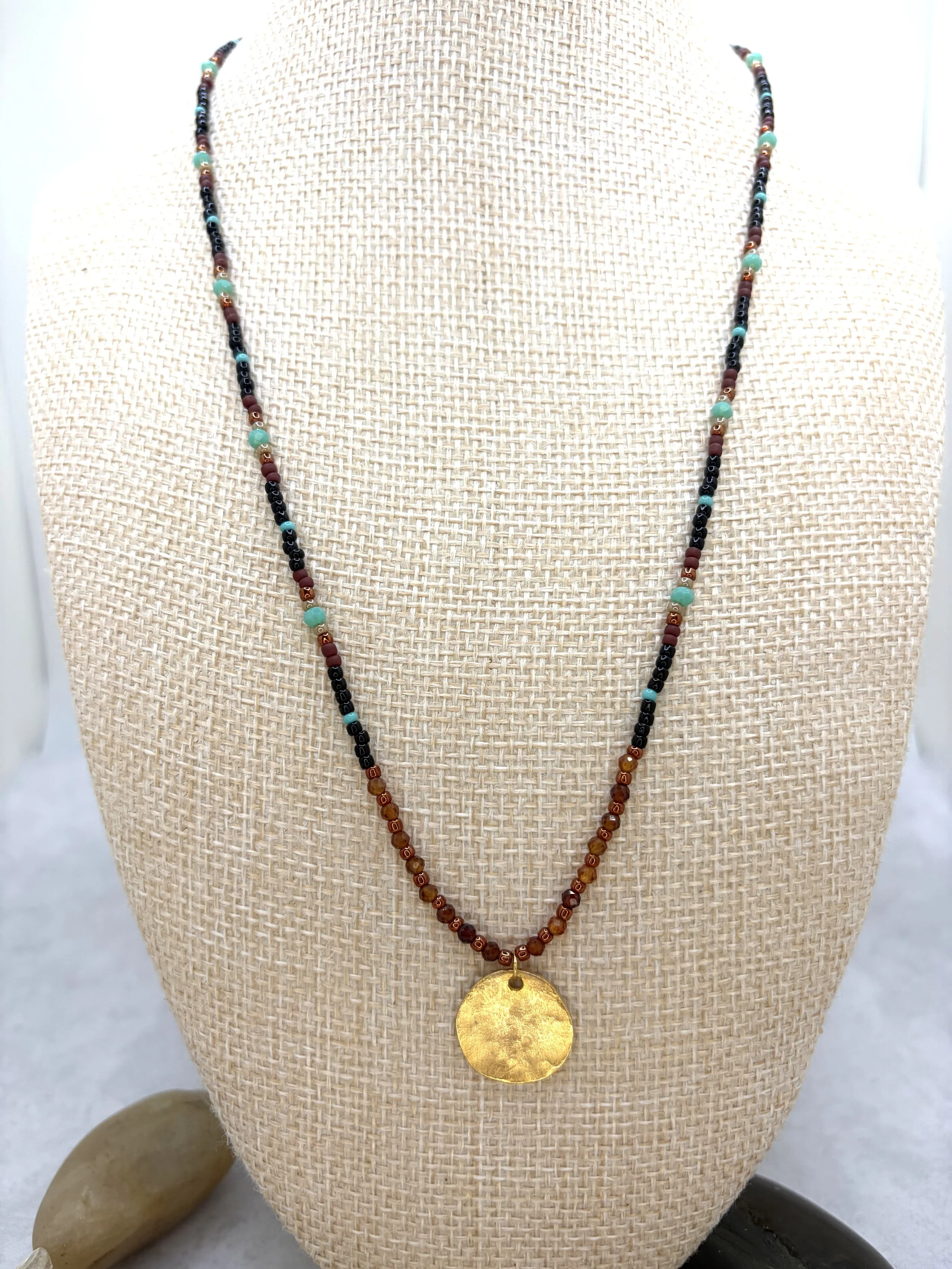 Handmade seed bead necklace with faceted garnet beads and a hammered gold-toned disc pendant