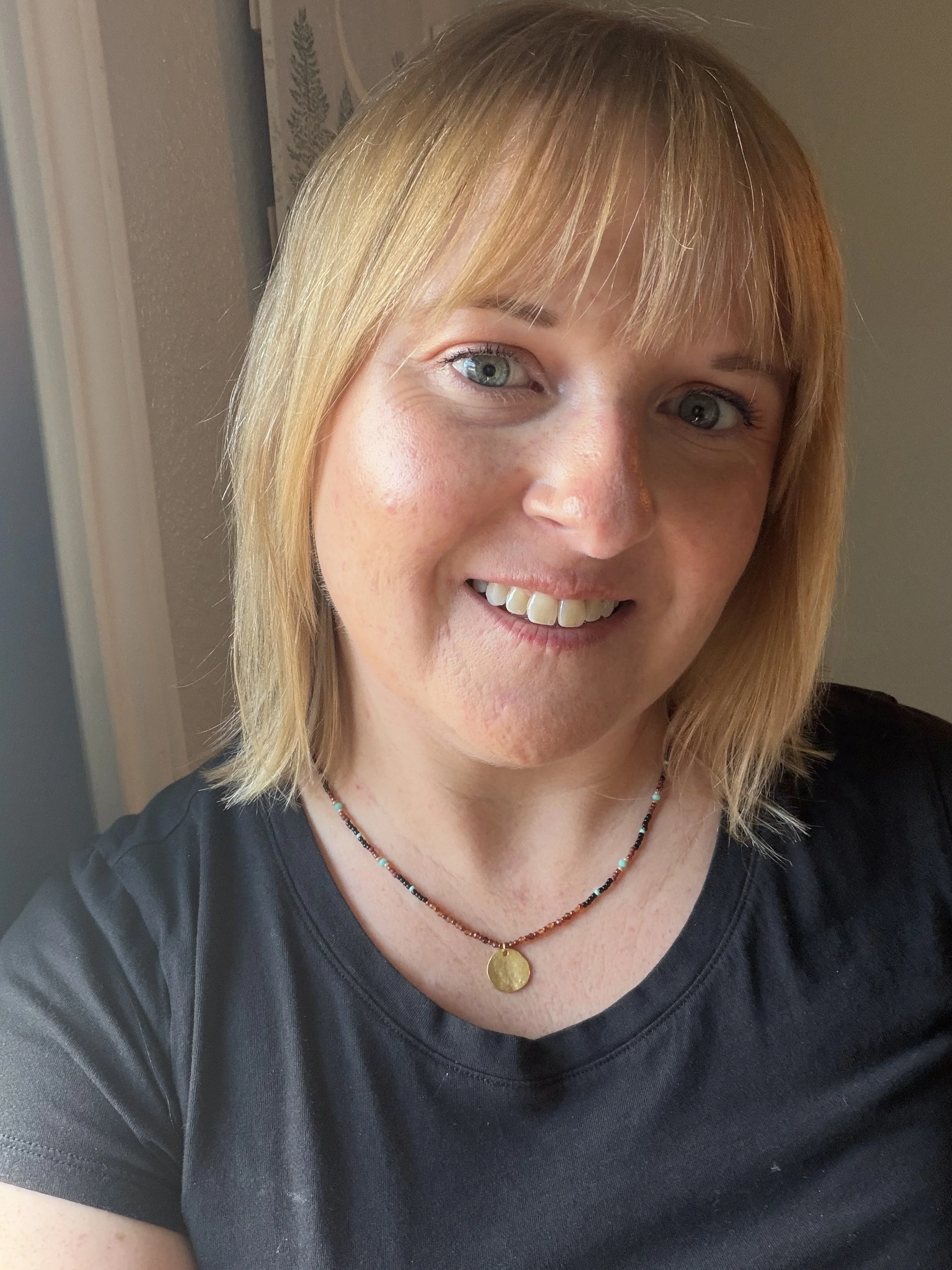 woman wearing Handmade seed bead necklace with faceted garnet beads and a hammered gold-toned disc pendant