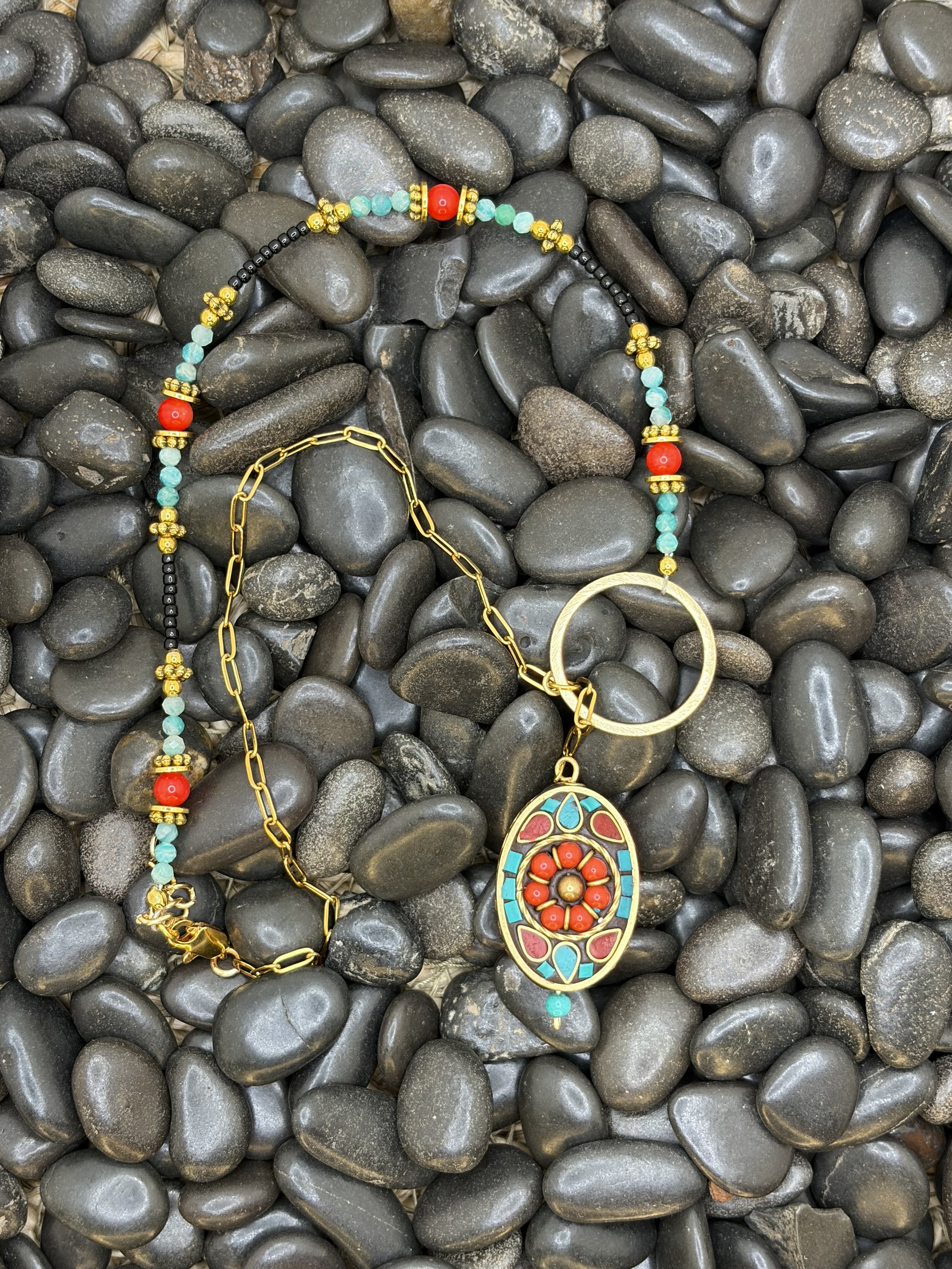 Handmade asymmetrical necklace with a Tibetan brass coral and turquoise howlite inlay pendant, red coral and amazonite beads, and a gold-toned paperclip chain