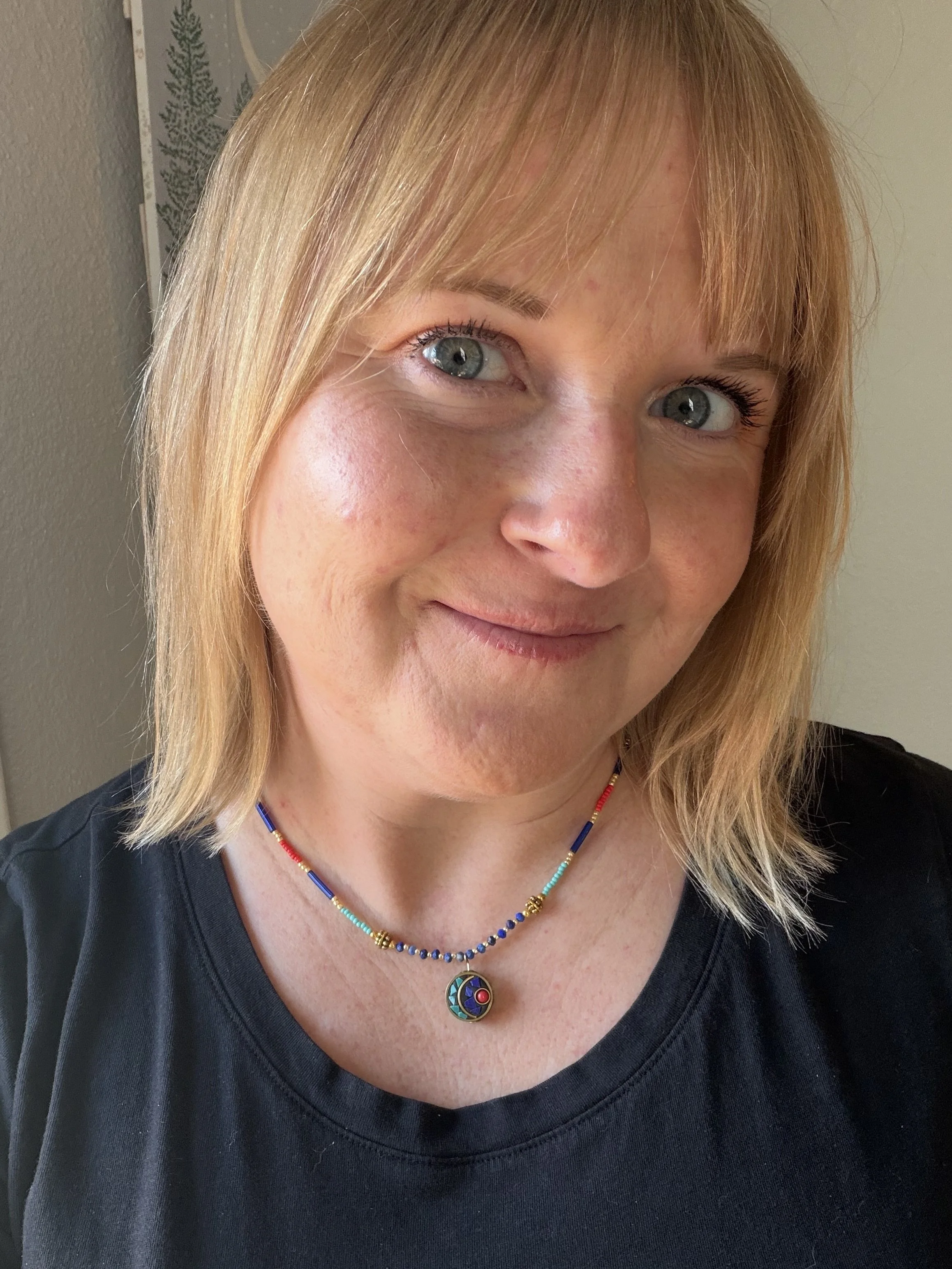 woman wearing handmade beaded necklace with round Tibetan brass turquoise coral inlay charm and faceted lapis lazuli beads