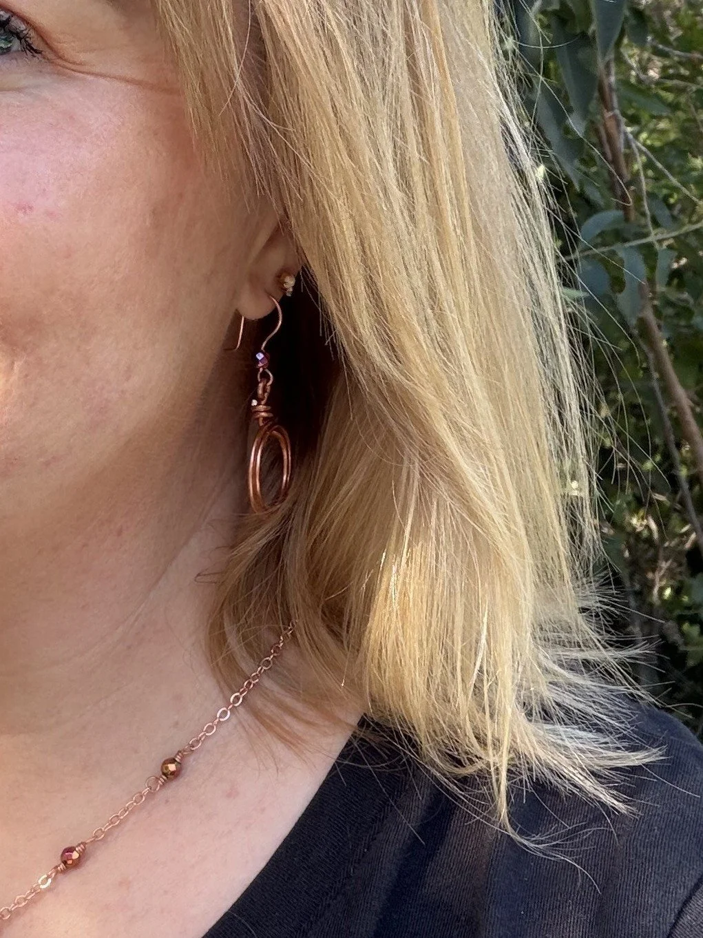 WOMAN WEARING handmade hammered copper double loop earrings with iridescent hematite accent bead