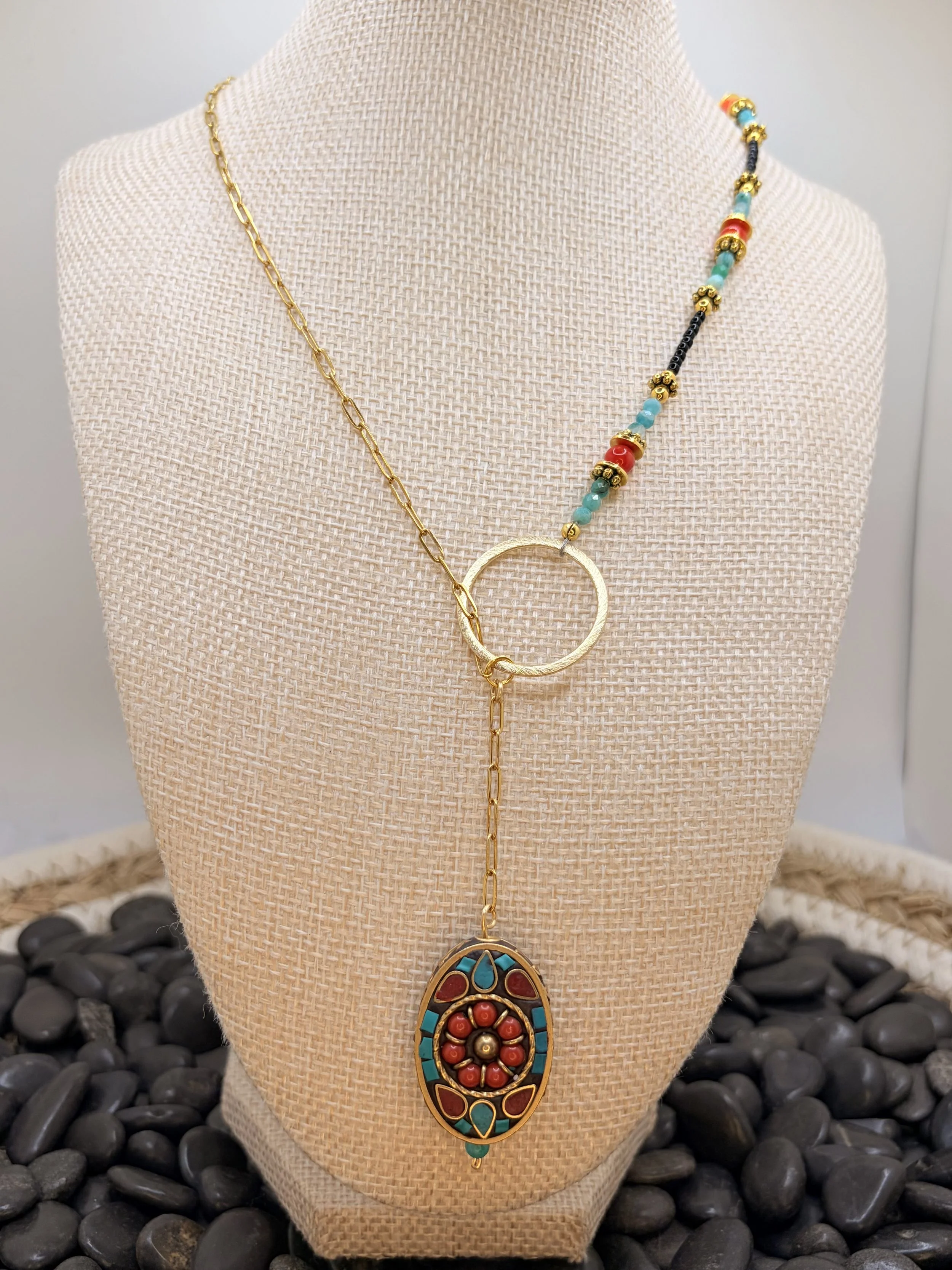 Handmade asymmetrical necklace with a Tibetan brass coral and turquoise howlite inlay pendant, red coral and amazonite beads, and a gold-toned paperclip chain