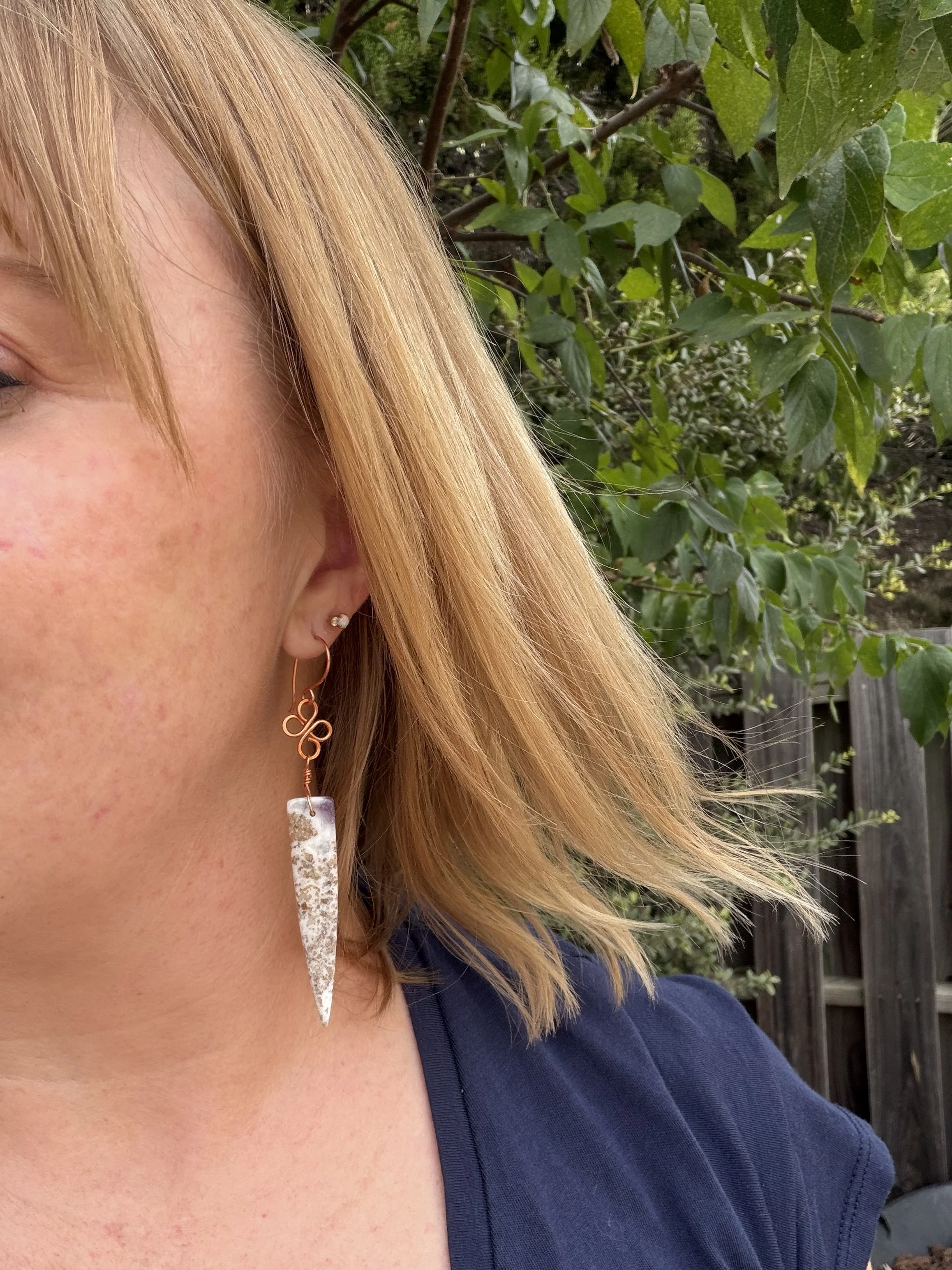 woman wearing handmade agate copper wire wrapped dagger earrings with copper clover-link connector