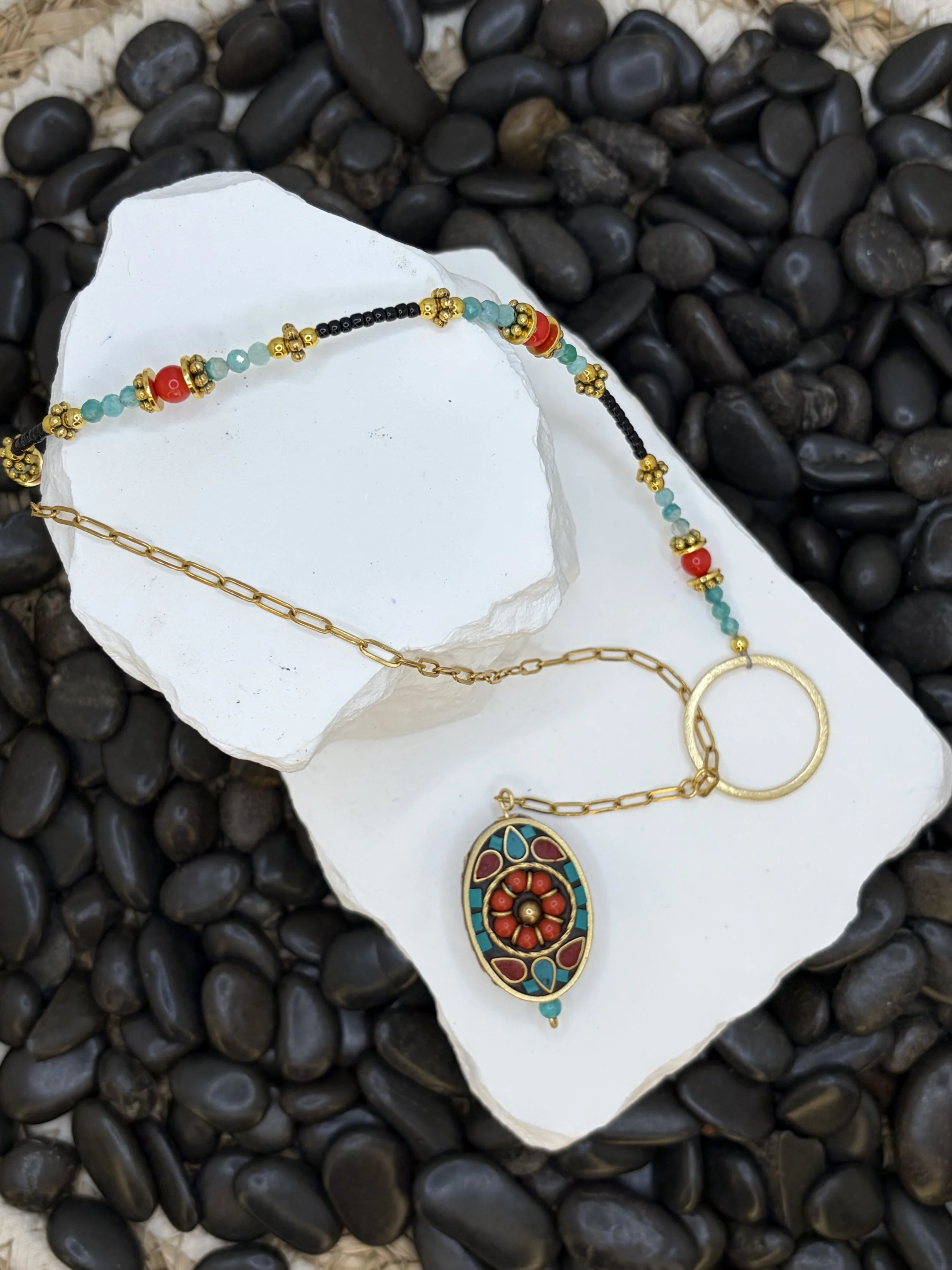Handmade asymmetrical necklace with a Tibetan brass coral and turquoise howlite inlay pendant, red coral and amazonite beads, and a gold-toned paperclip chain