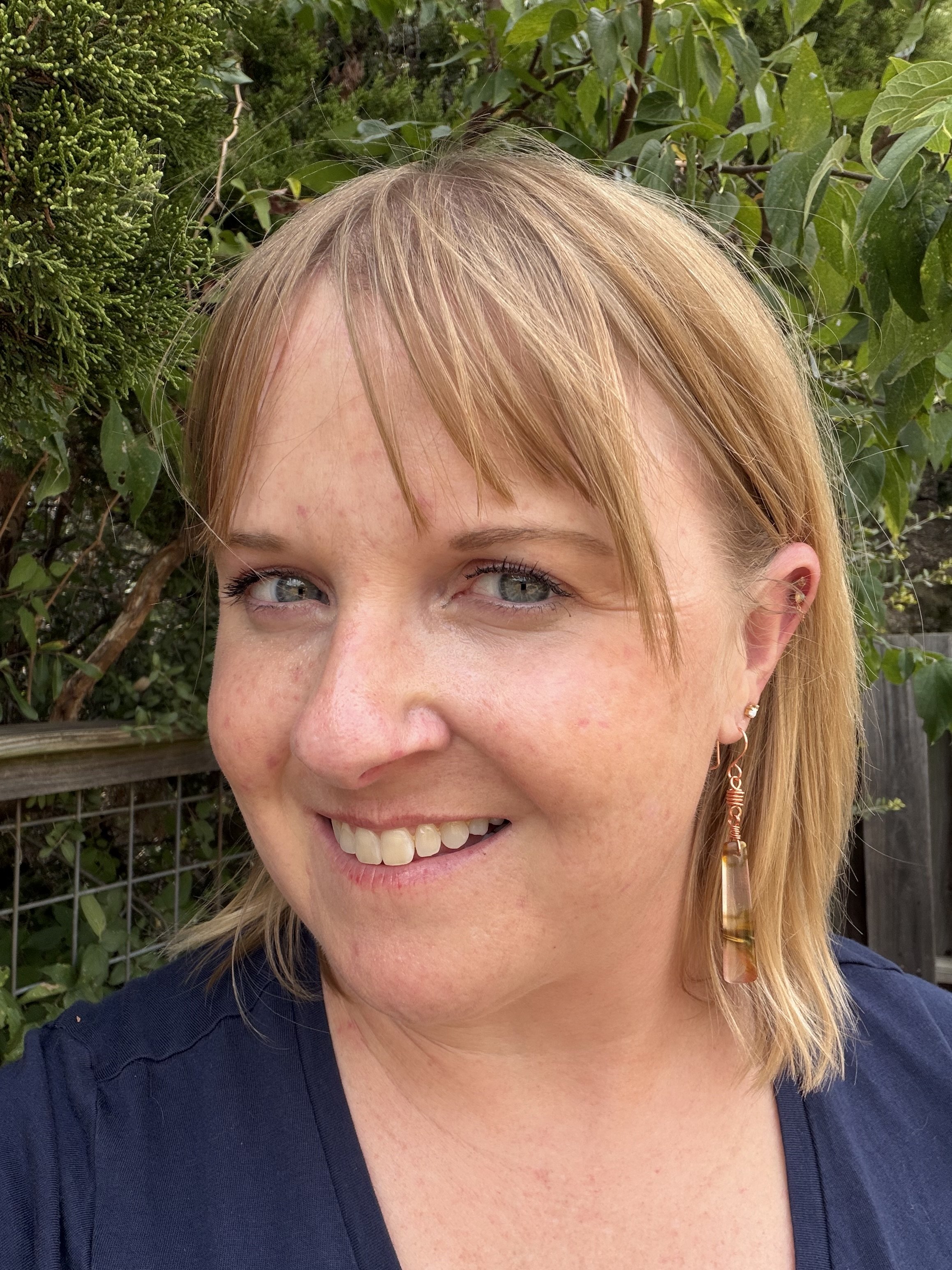 woman wearing handmade desert jasper copper wire wrapped earrings with coiled copper barrel link